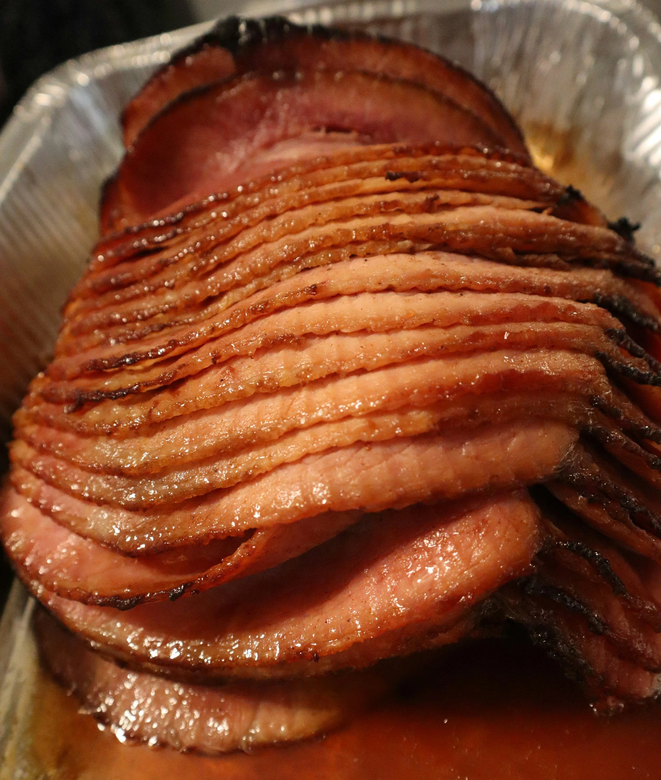Close-up of crisscrossed slices of cooked bacon inside a foil container.