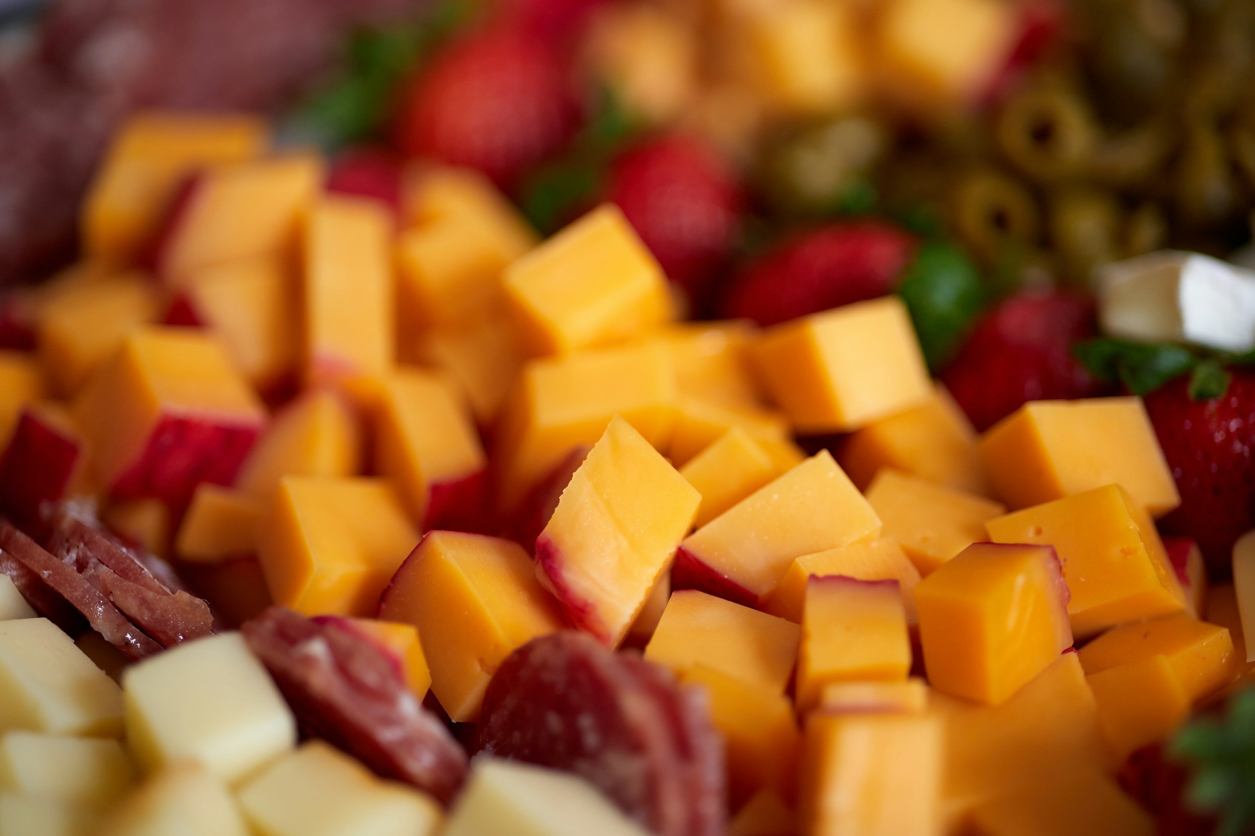 Close-up of cubed cheese, strawberries, and other fruits on a platter.