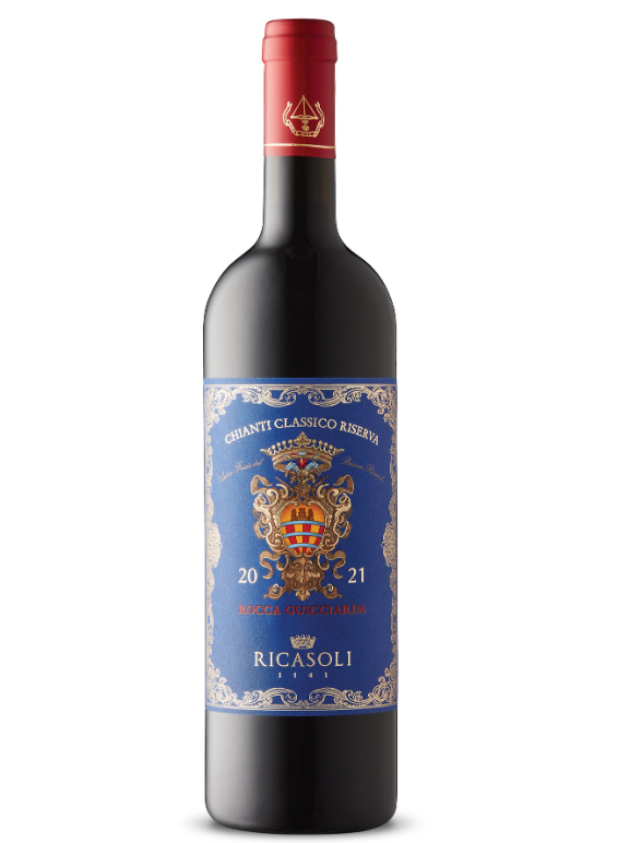 A bottle of Ricasoli Chianti Classico Riserva wine with a black body, red capsule, and a blue label featuring a crest, gold accents, and white ornate designs.