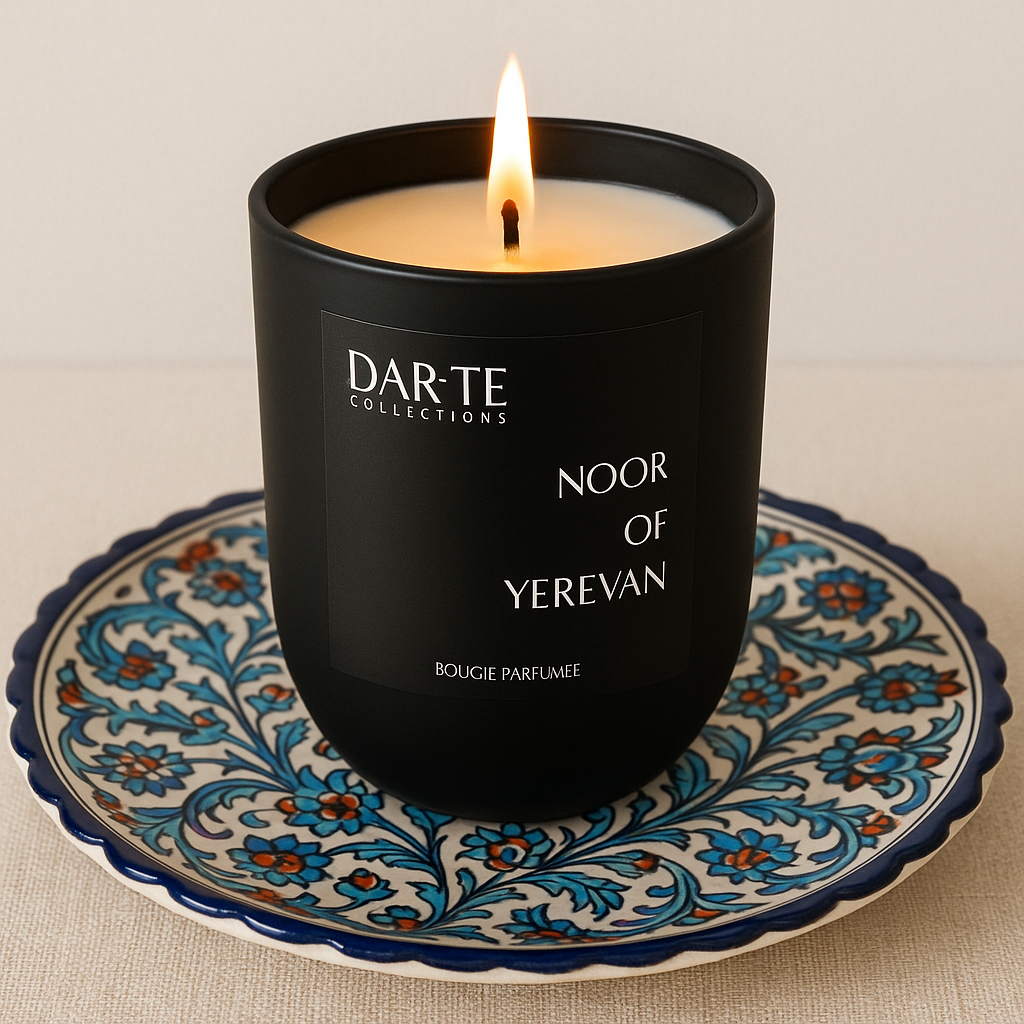Black scented candle labeled "Noor of Yerevan" on an ornate blue, orange, and white decorative plate.