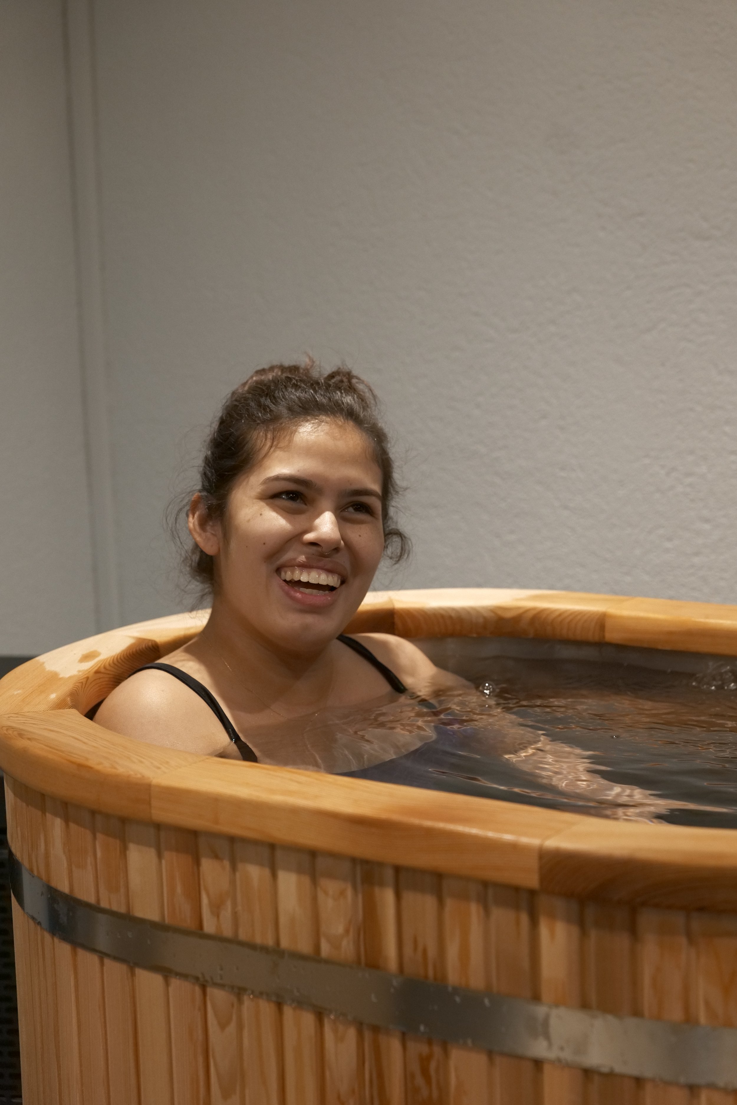 Deux baignoires en bois avec deux petites escaliers en bois devant, sur un fond de mur blanc avec l'inscription "Mettre du confort dans l'inconfort" en lettres noires.