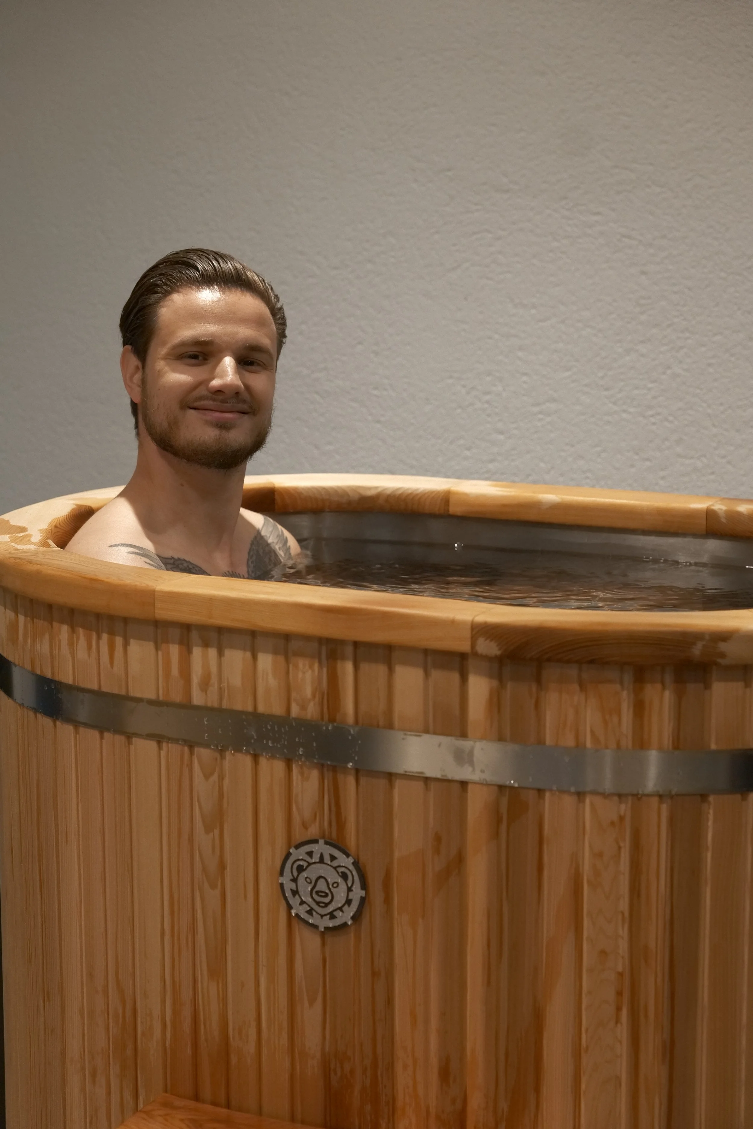 Deux baignoires en bois avec deux petites escaliers en bois devant, sur un fond de mur blanc avec l'inscription "Mettre du confort dans l'inconfort" en lettres noires.