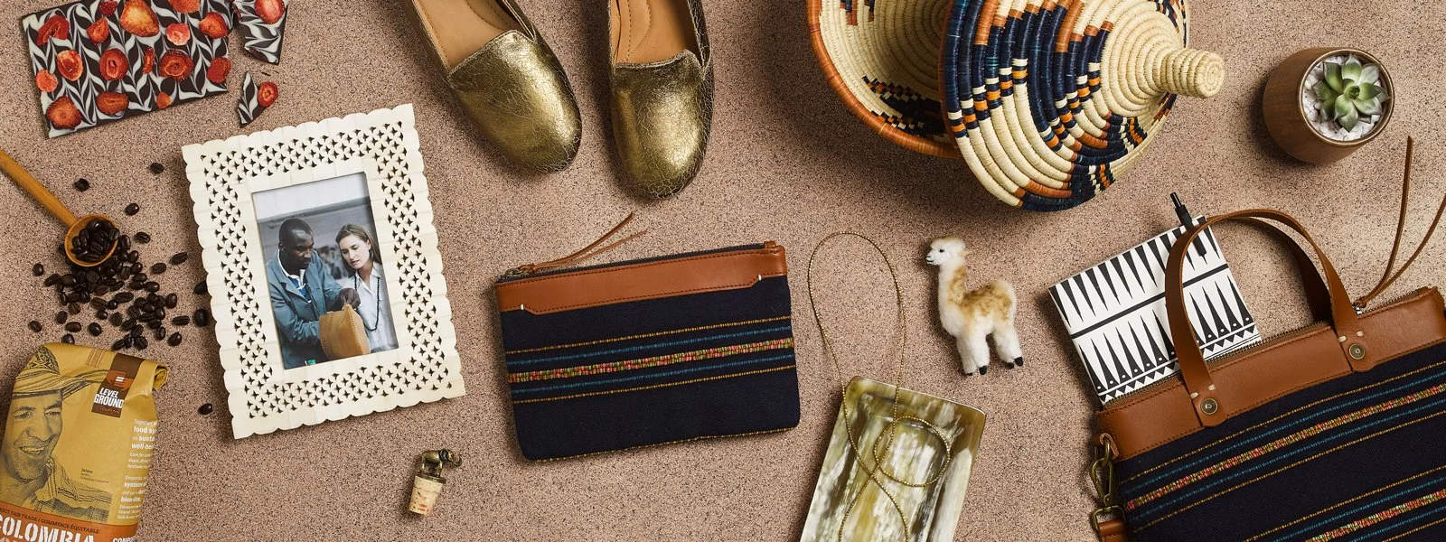 Flat lay of various travel and fashion accessories, including jewelry, shoes, a framed photo, a small llama figurine, a bag, and a patterned hat on a textured surface.