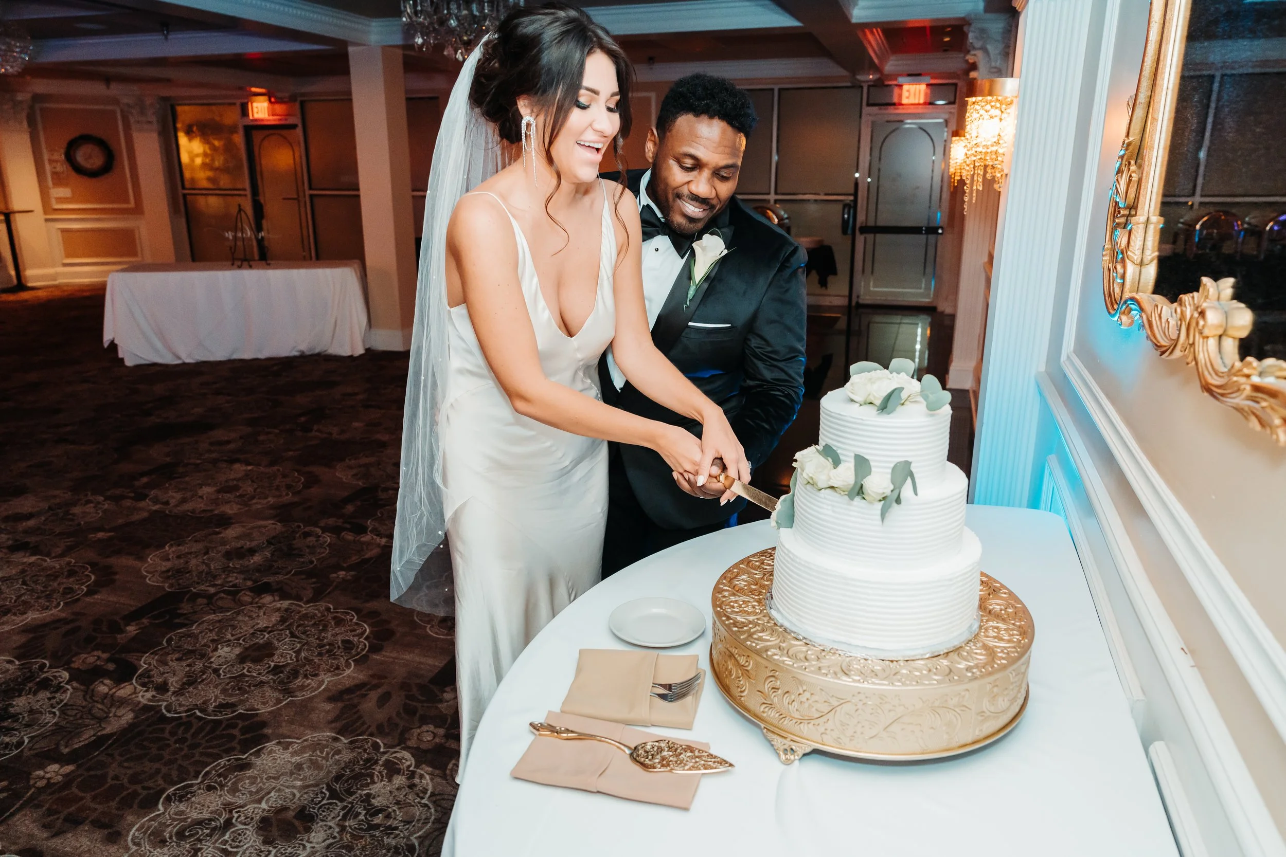 Bride and groom cutting wedding cake in reception hall