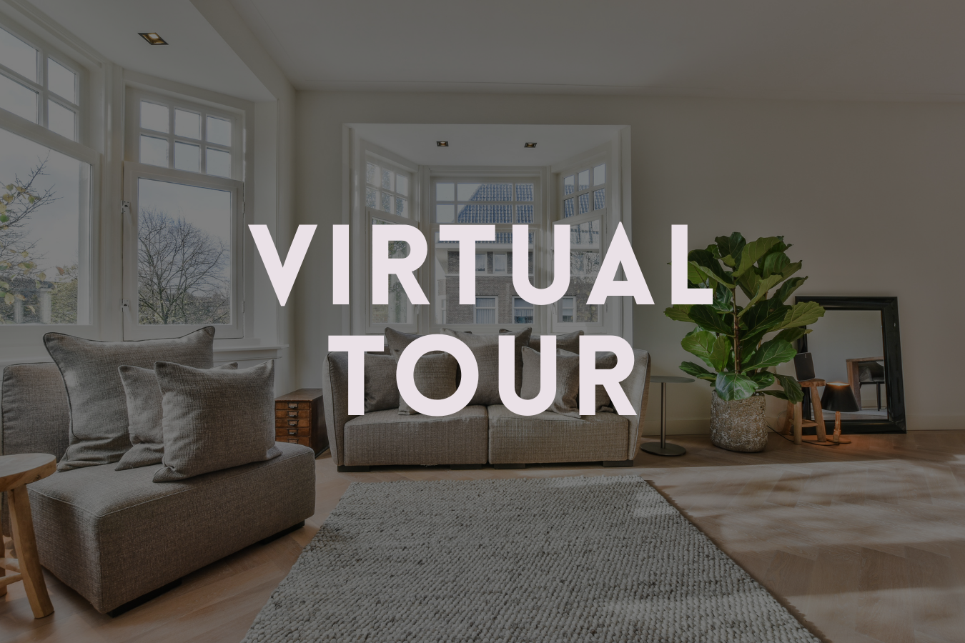 Living room with large windows, beige sofas, a potted plant, and a mirror on the floor