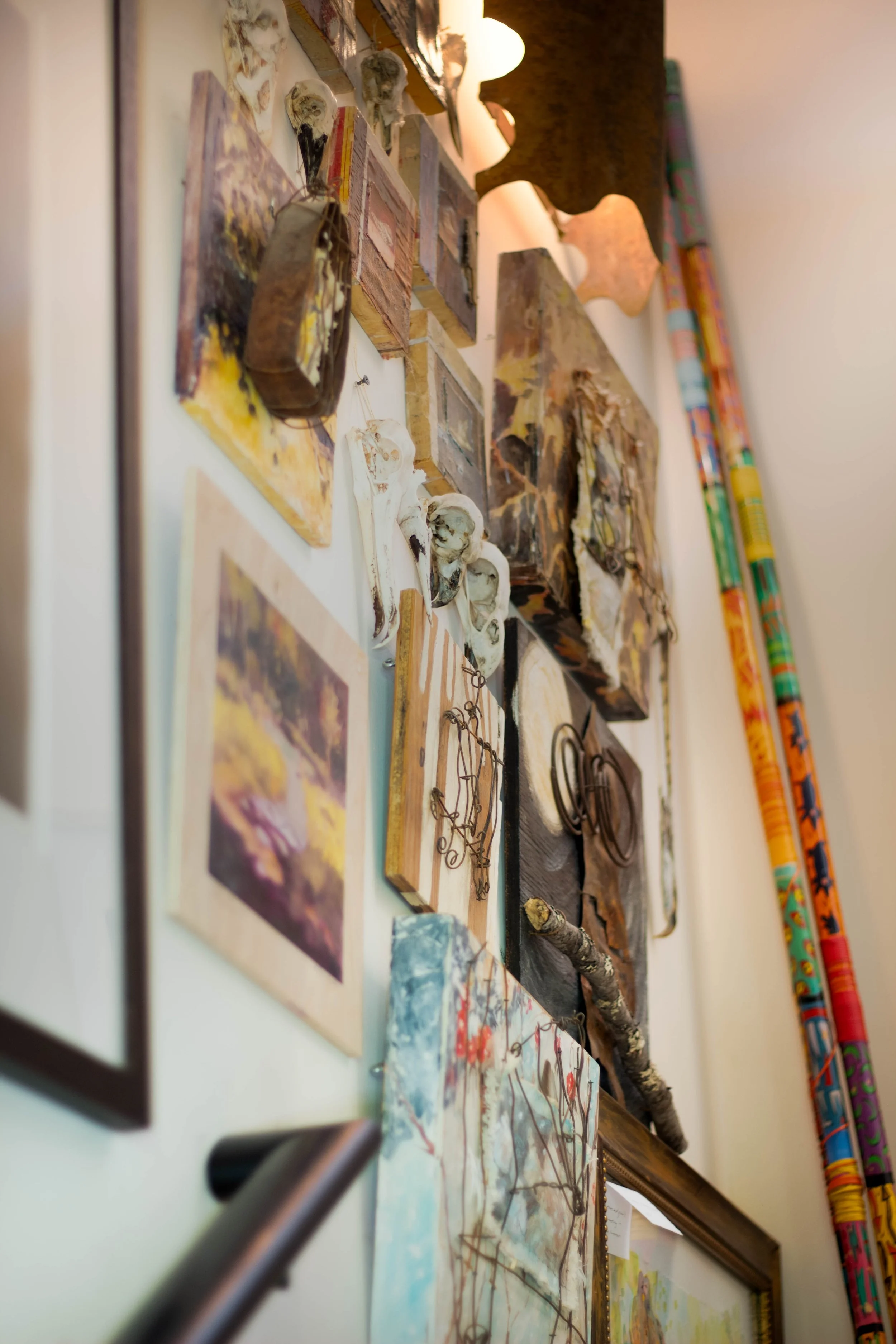 Close-up view of wall art and small sculptures or model heads, with paintings, decorative items, and colorful rolled-up posters on the wall.