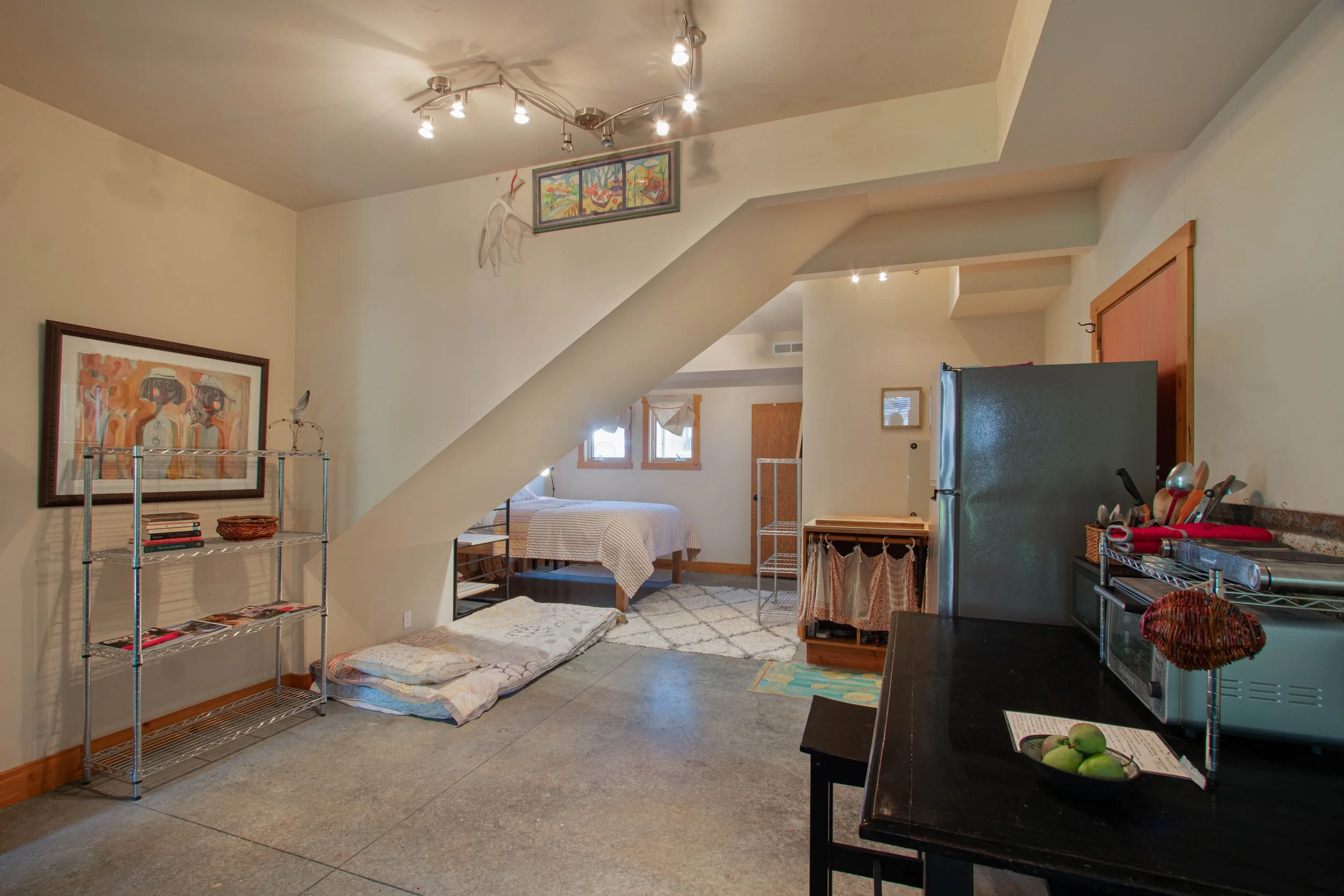 Cozy studio apartment with a bed, small kitchen area, and various decorative elements.