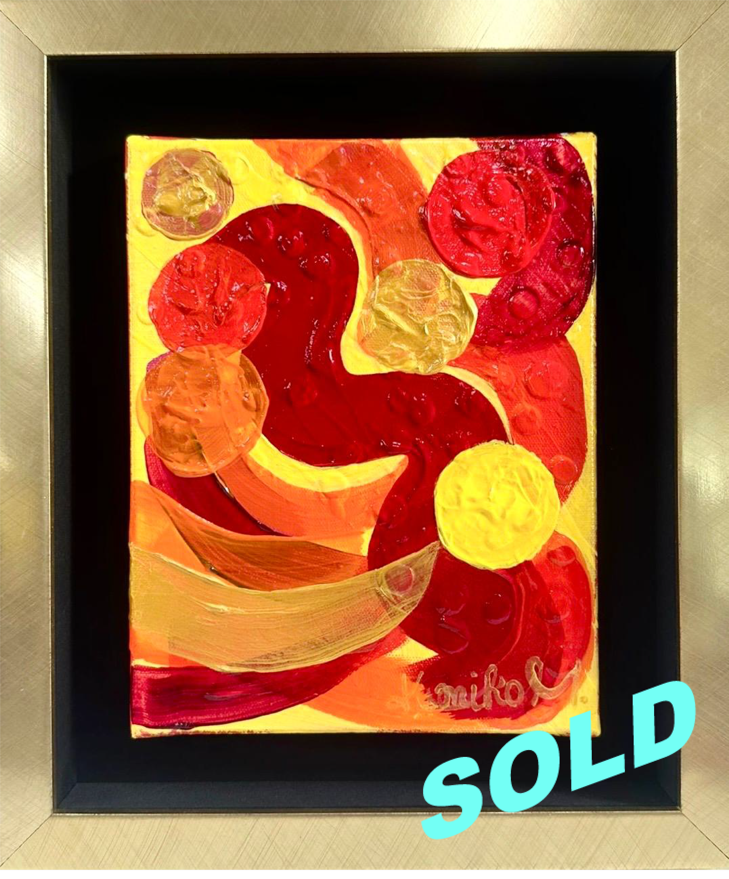 Abstract mixed media artwork with swirls of red, orange, and yellow, featuring circular and curved shapes, framed in black with a light background, and the word 'SOLD' in blue text at the bottom right corner.