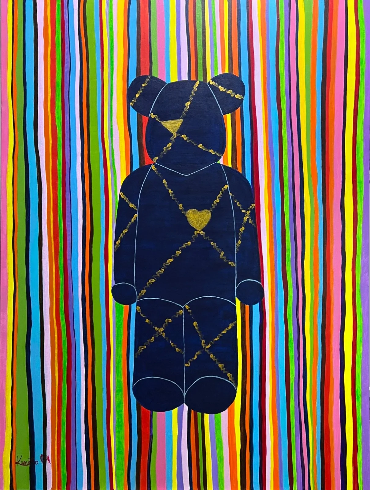 A dark coloured bear with golden paint painted across in a colourful stripe background.