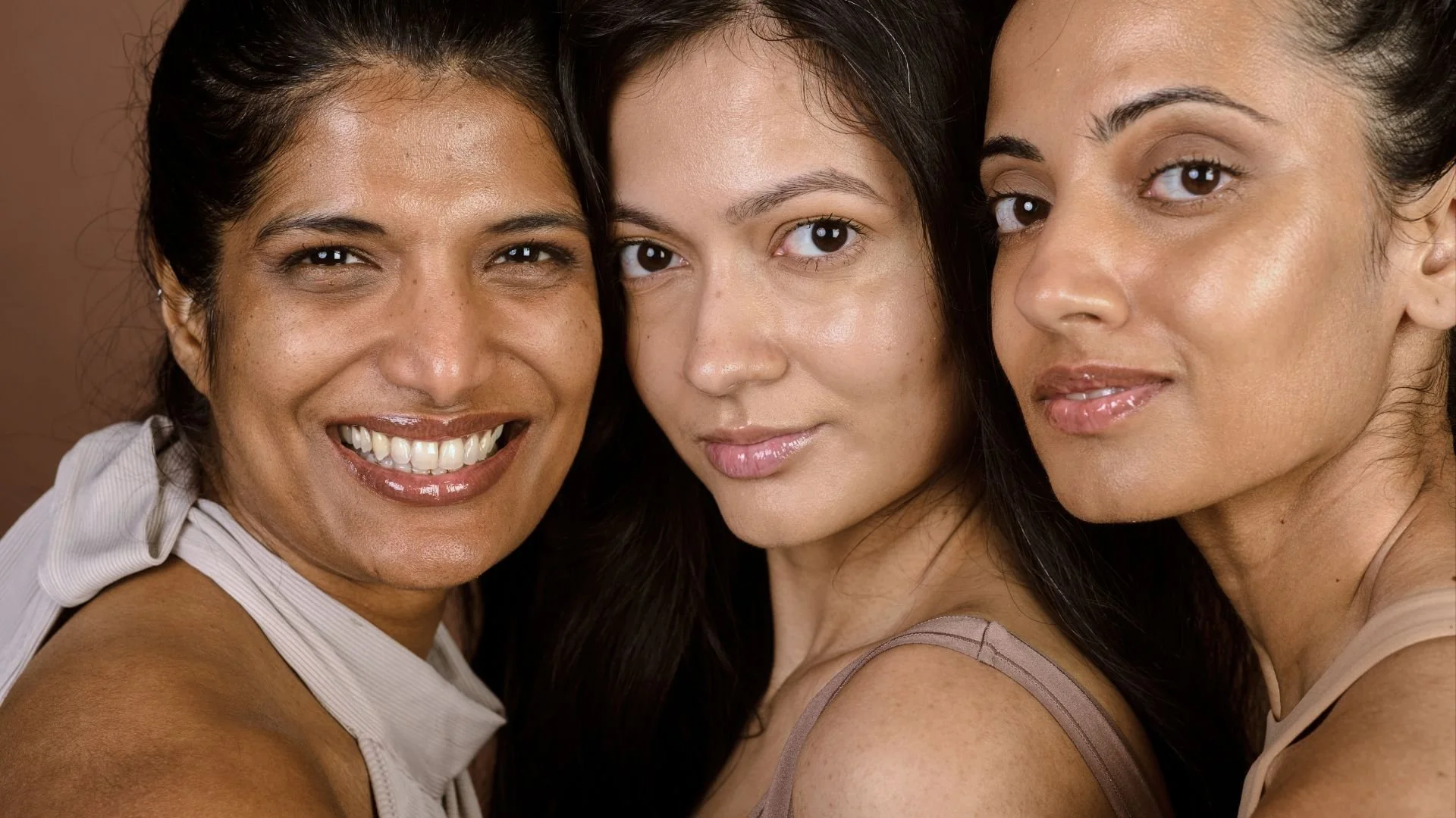 Close-up of three women smiling and standing close together
