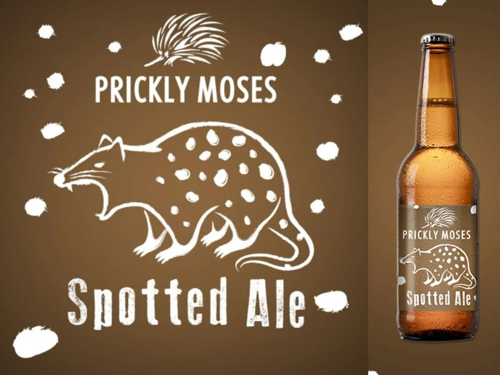 A beer bottle with a label featuring a white illustration of a spotted mouse and text reading "Prickly Moses" and "Spotted Ale," next to a wall with matching branding and a quoll illustration.