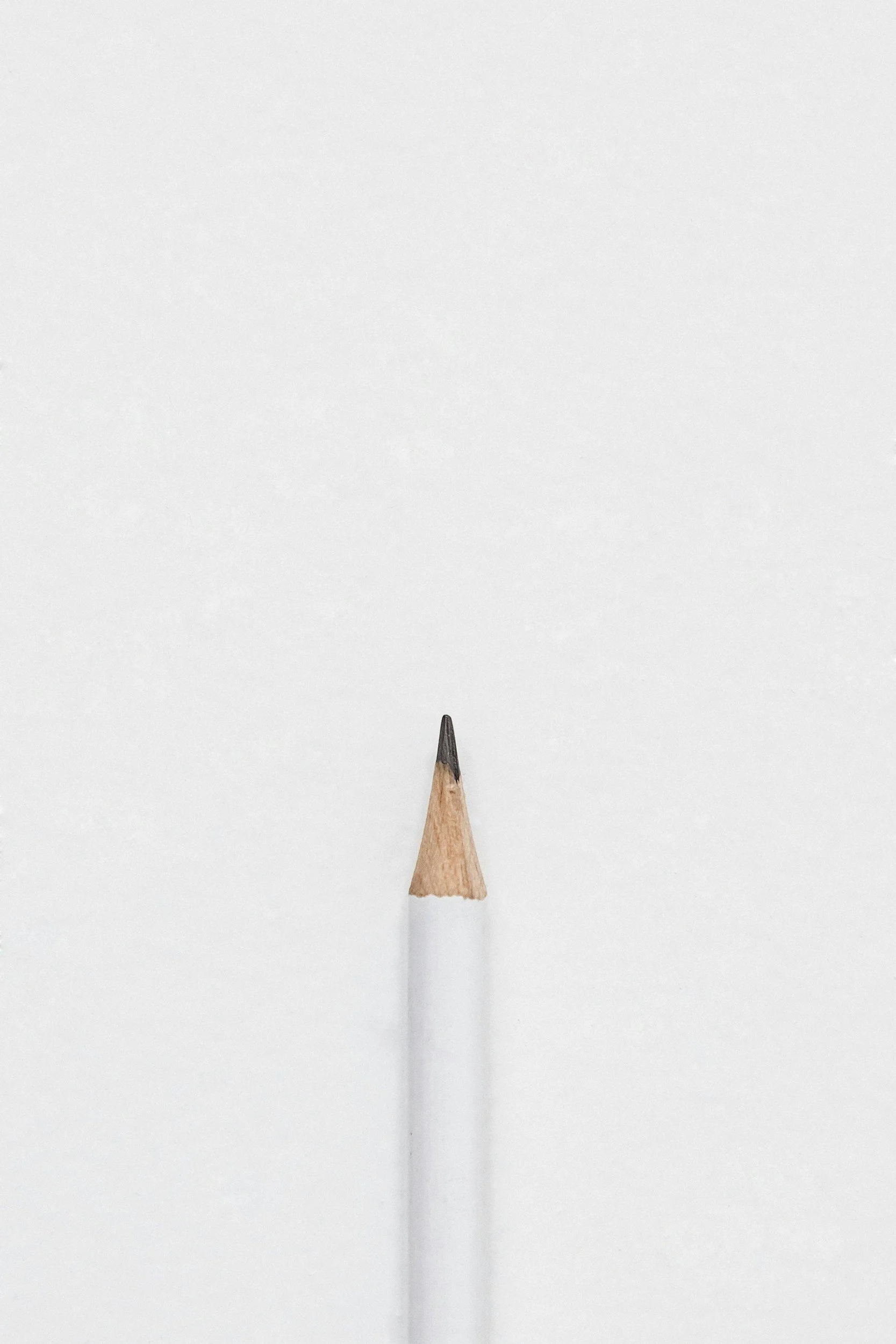 Close-up of a sharpened white pencil with a black tip against a plain white background.