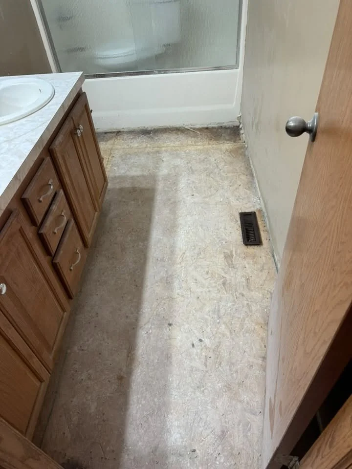 Bathroom demolition in Wichita, KS: vanity area and floor stripped to the subfloor