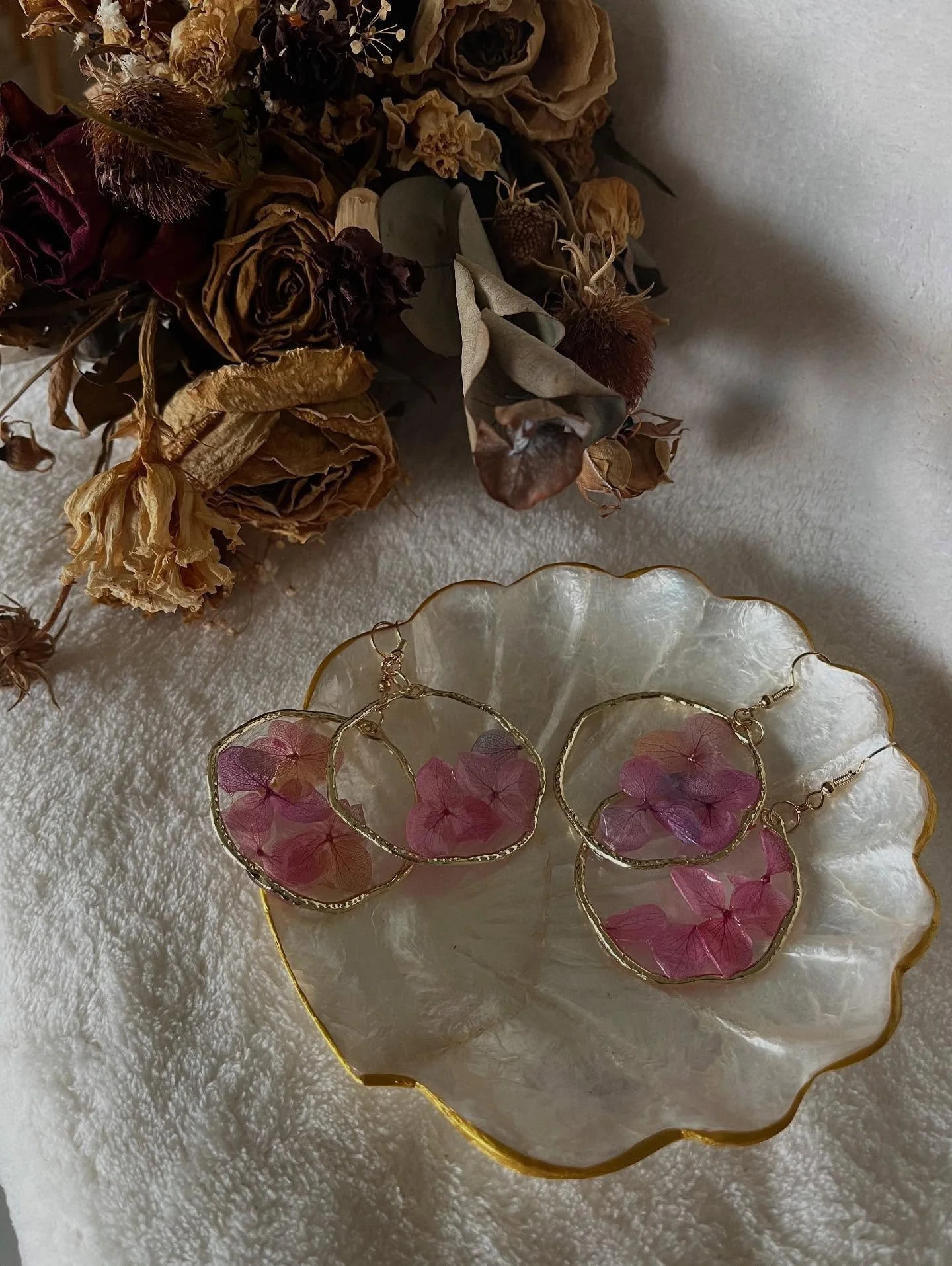 Helena 

Fuchsia and purple hydrangeas delicately preserved in resin and framed within a golden hoop &mdash; a striking floral statement; vibrant yet graceful.