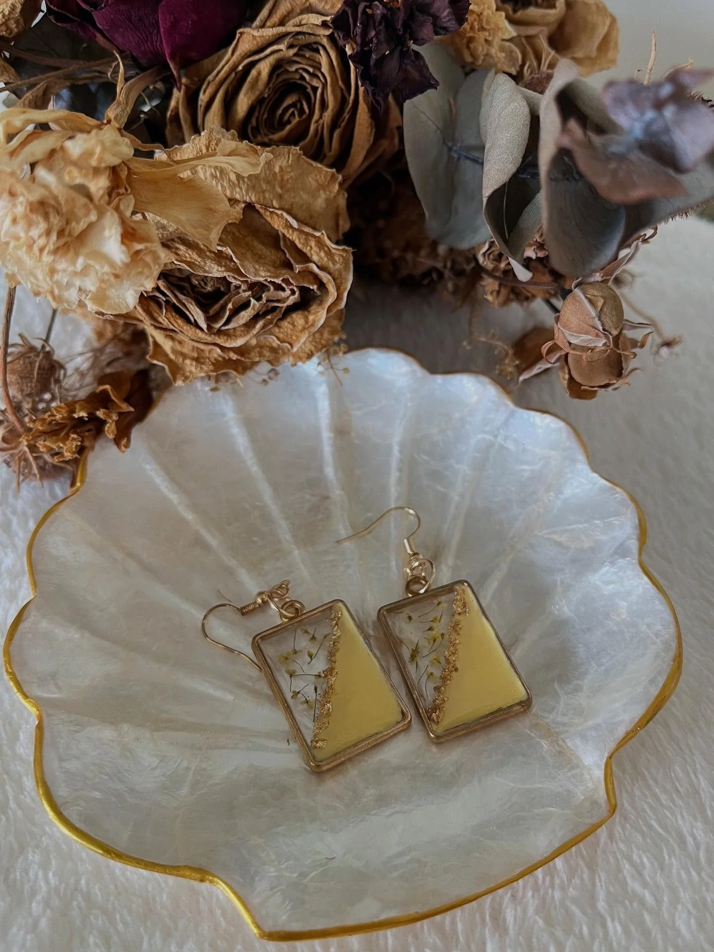 Joy

Pressed florals, creamy yellow tones, and flecks of gold shimmer come together in clear resin, all delicately set in a gold bezel. A gentle bloom you can wear.