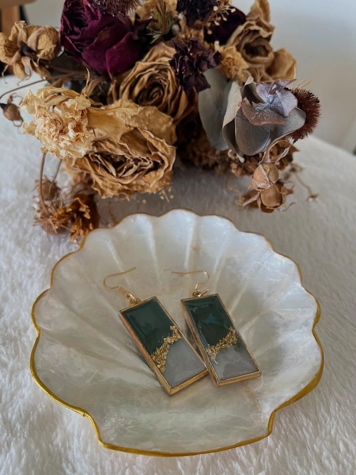 Olivia

A timeless blend of jade green, soft white, and delicate gold flakes, captured in clear resin and framed by a gold bezel. These earrings are a quiet statement &mdash; graceful, grounded, and effortlessly refined.