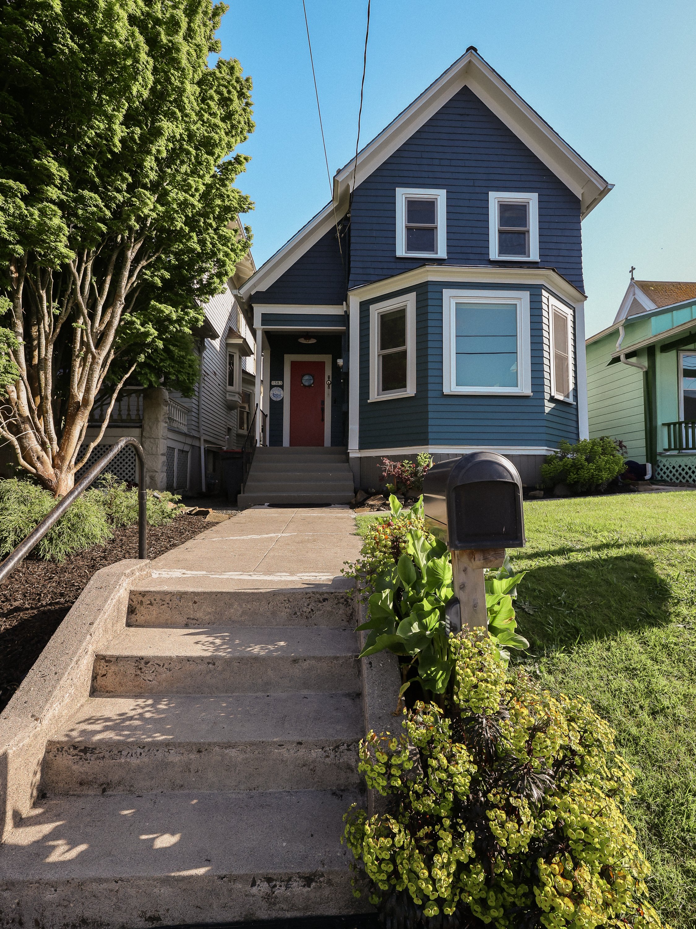 The fix: We started with the tomato red door and chose the home body paint color to be a deep sea green, reflecting colors of the mighty Columbia River. The trim is a classic white, giving a bold nautical aesthetic.