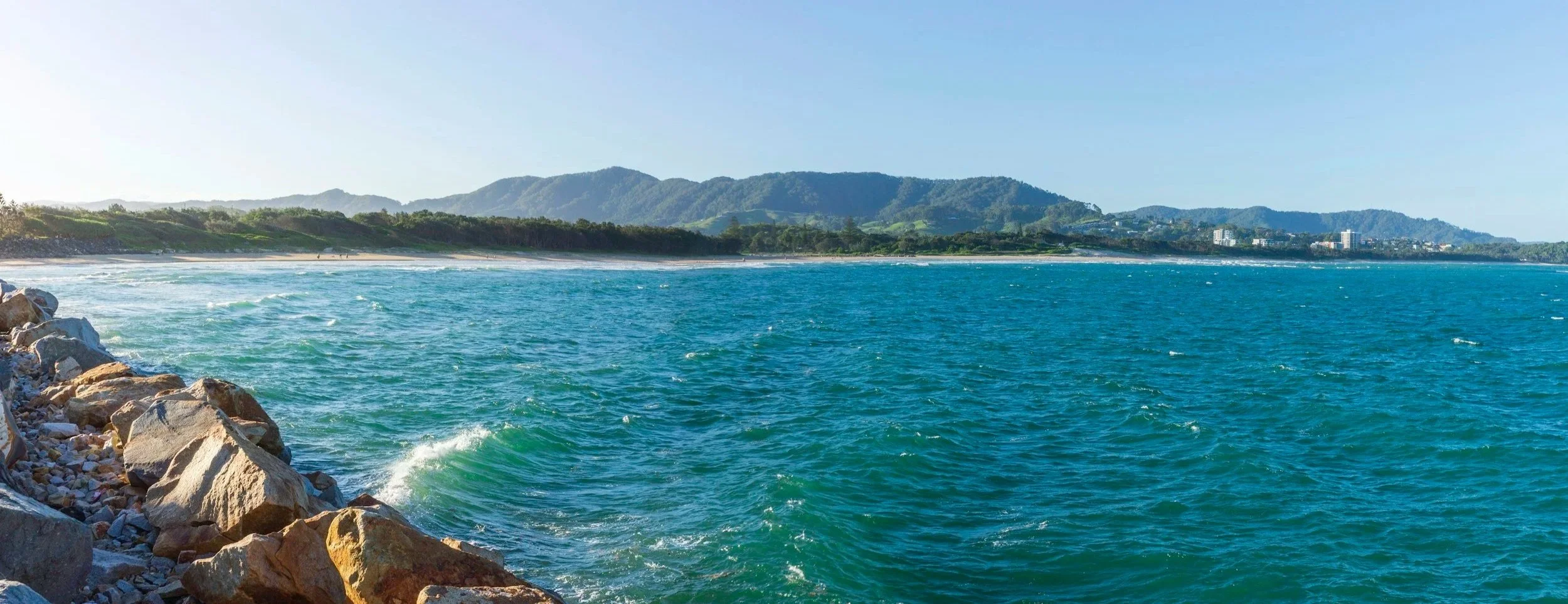 Coffs Harbour Jetty beach with mountains in the background.