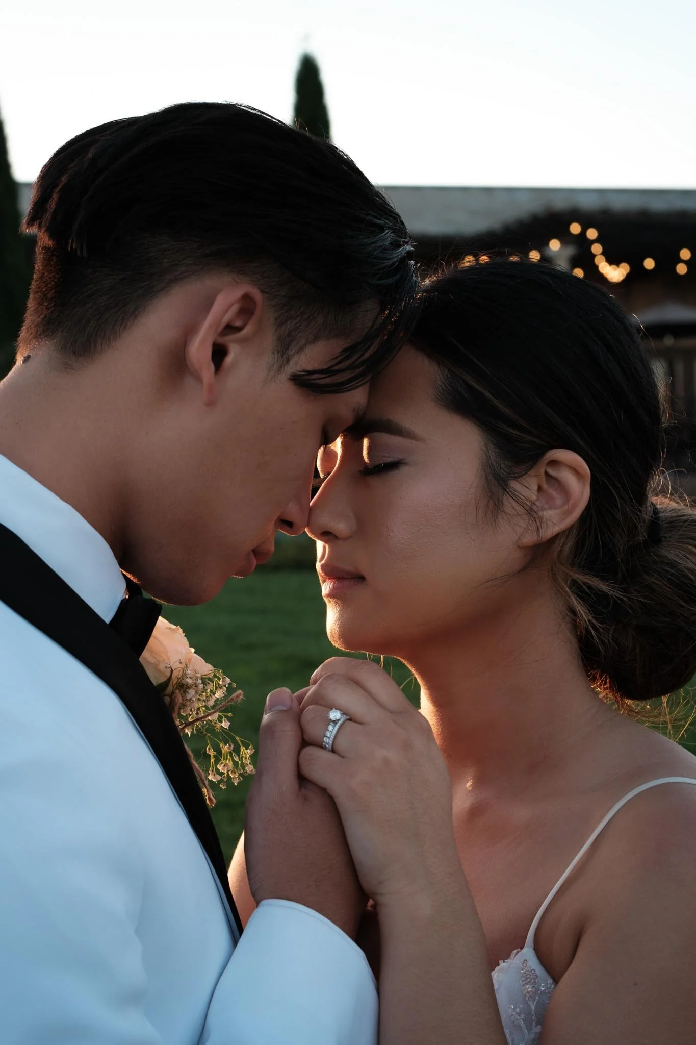 Bride and groom holding hands with their foreheads together in an intimate moment in front of their wedding venue in Nebraska at sunset