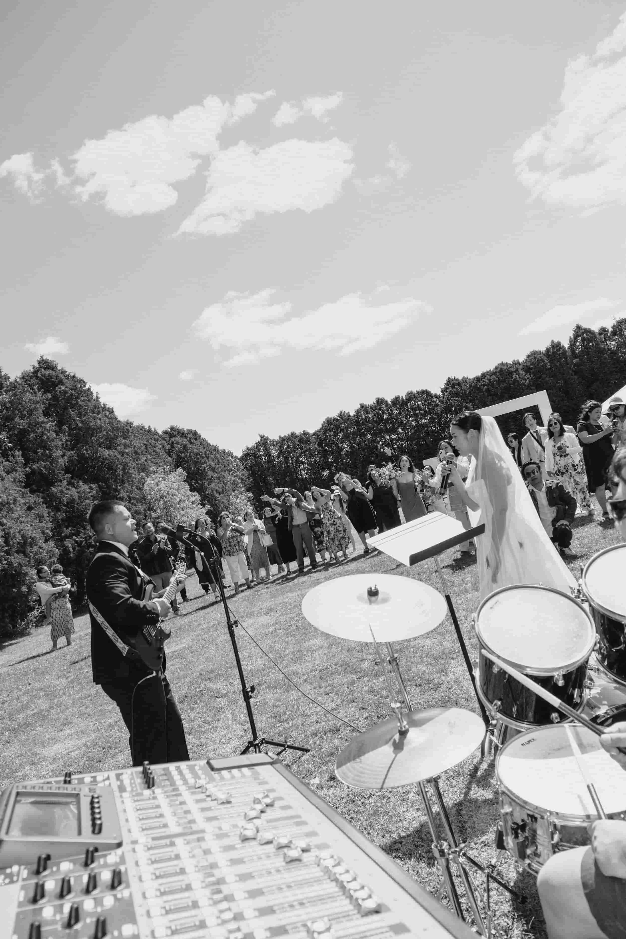 Candid wedding moment of a couple singing together as the groom plays guitar and the bride leads a love song while guests cheer them on