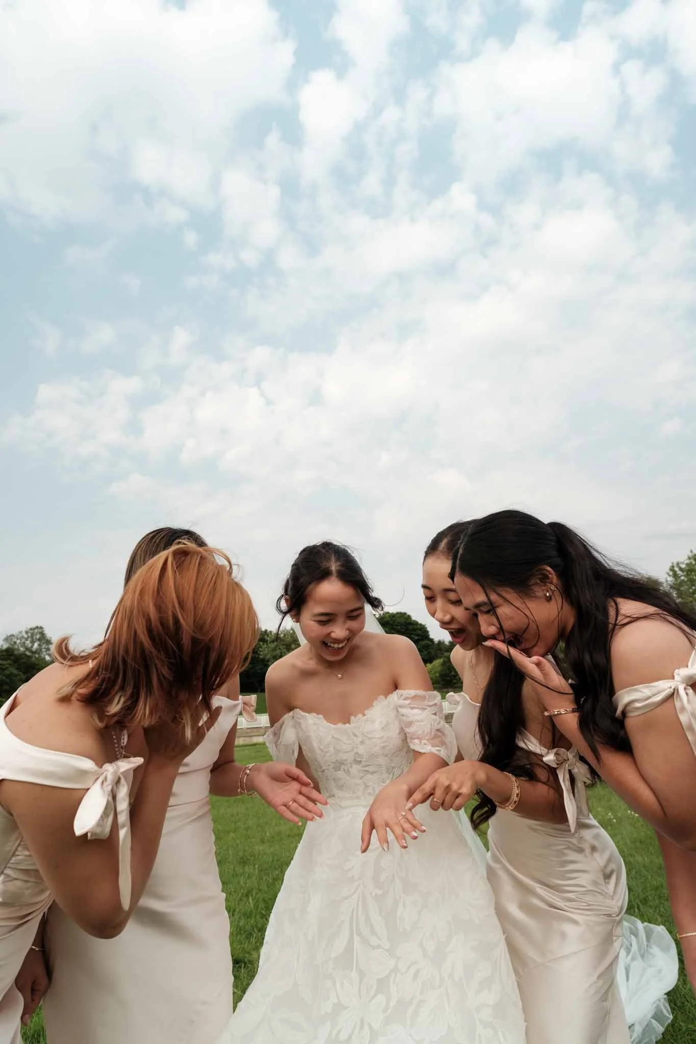 Bride showing off her wedding ring to her bridesmaids, who look amazed and happy for her