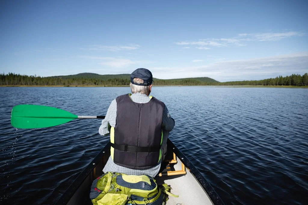 Mann fährt im Kanu in Lappland