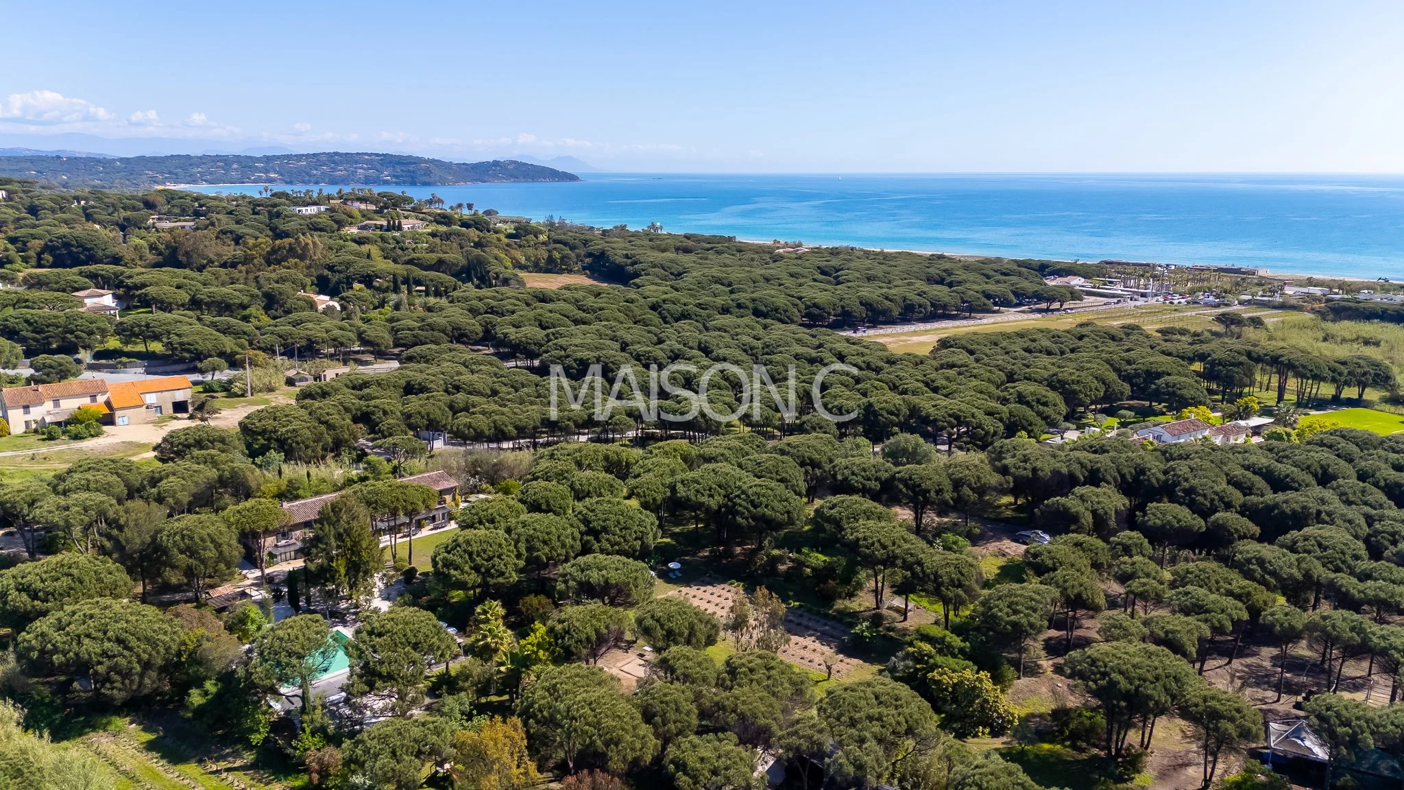 Vue aérienne d'une zone côtière avec des arbres verts, des maisons et la mer en arrière-plan