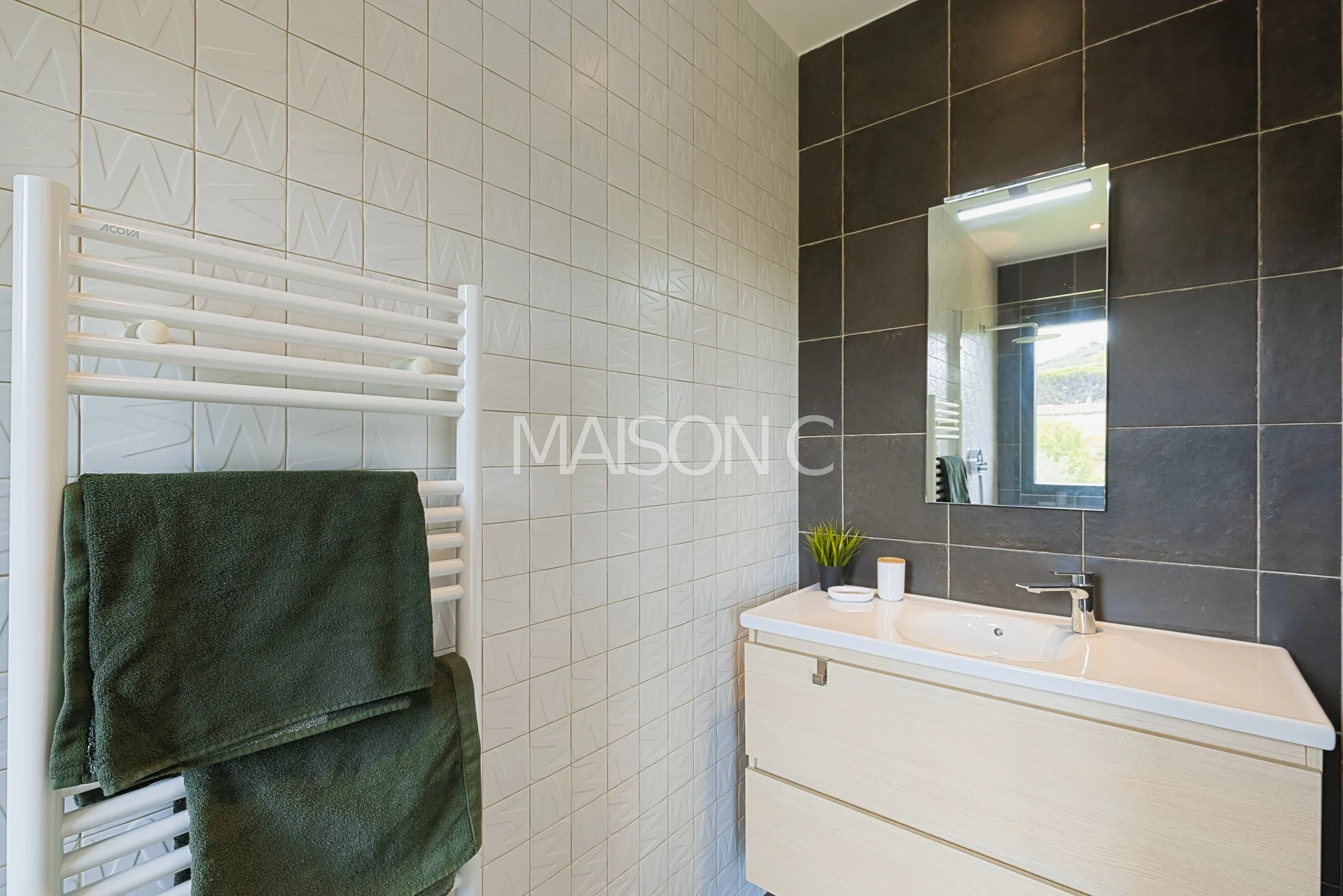 Salle de bain avec miroir, lavabo, plantes vertes et serviettes vertes