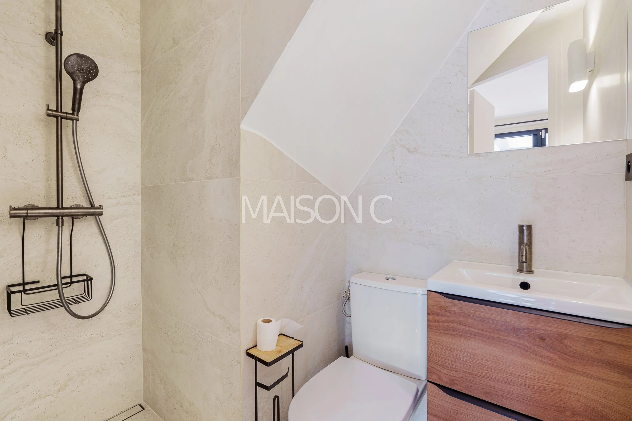Salle de bain moderne avec douche, toilette, petit lavabo avec meuble en bois, miroir et lumière