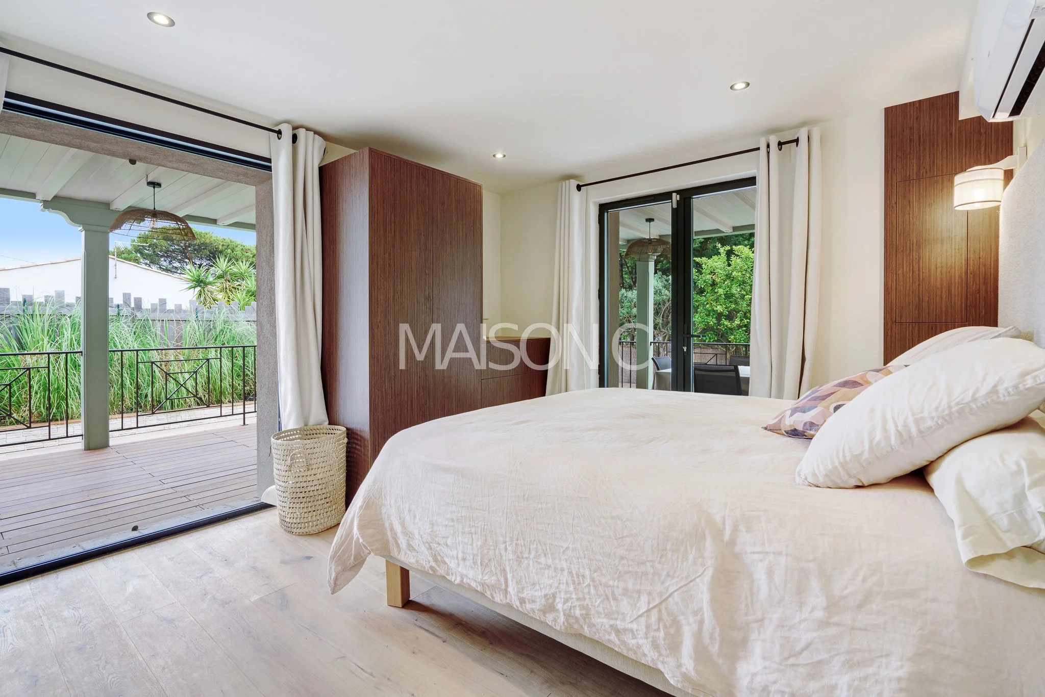 Chambre avec lit queen size, grande fenêtre avec portes-fenêtres donnant sur un balcon, vue sur la nature, décor moderne et lumineux.