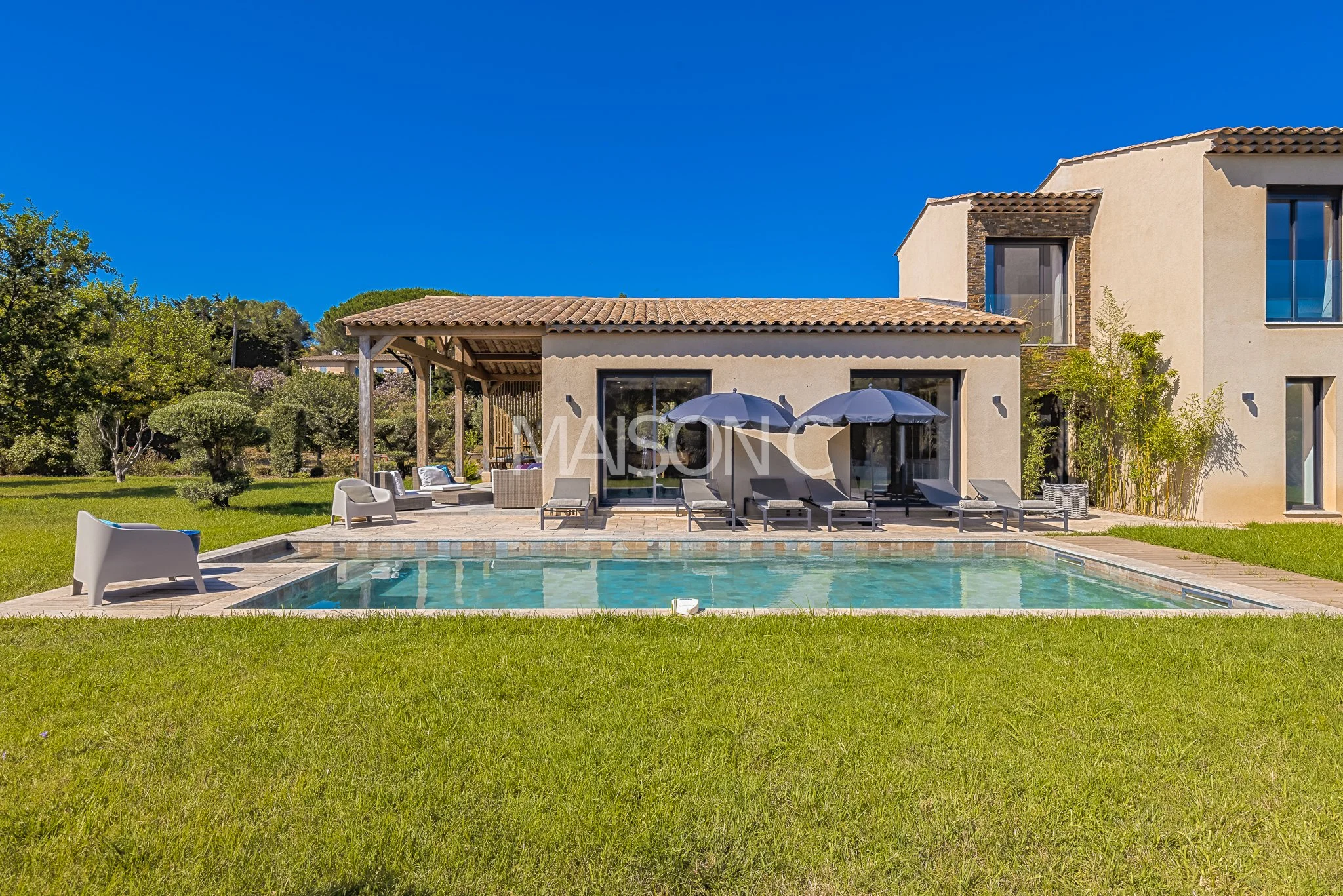 Maison moderne avec piscine et espace détente en plein air, avec mobilier et parasols