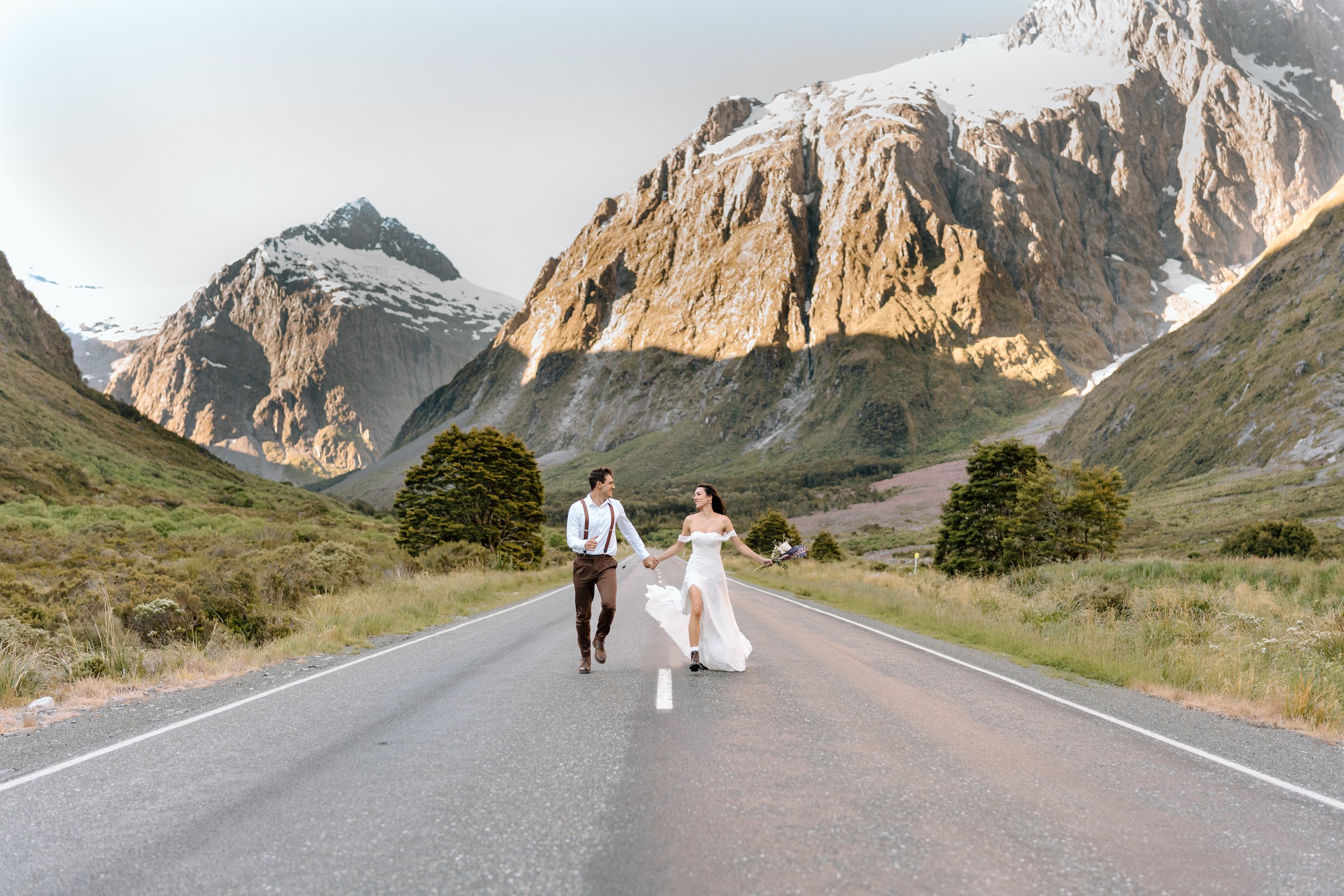 Wedding couple running on a road in Milford Sound