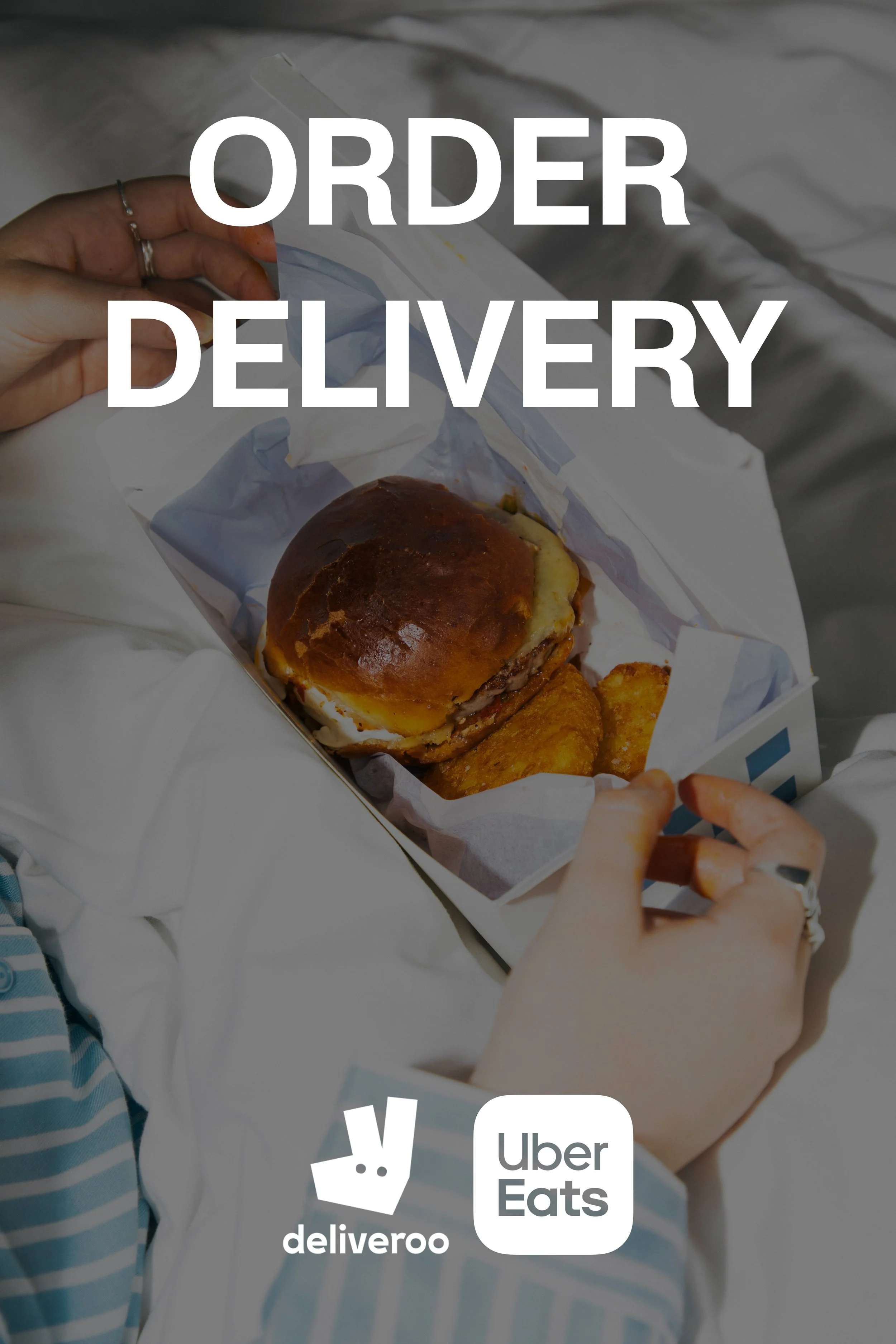 A person holding a cardboard food container with a cheeseburger and fried potato wedges, with the text "Order Delivery" overlaid and Uber Eats and Deliveroo logos at the bottom.