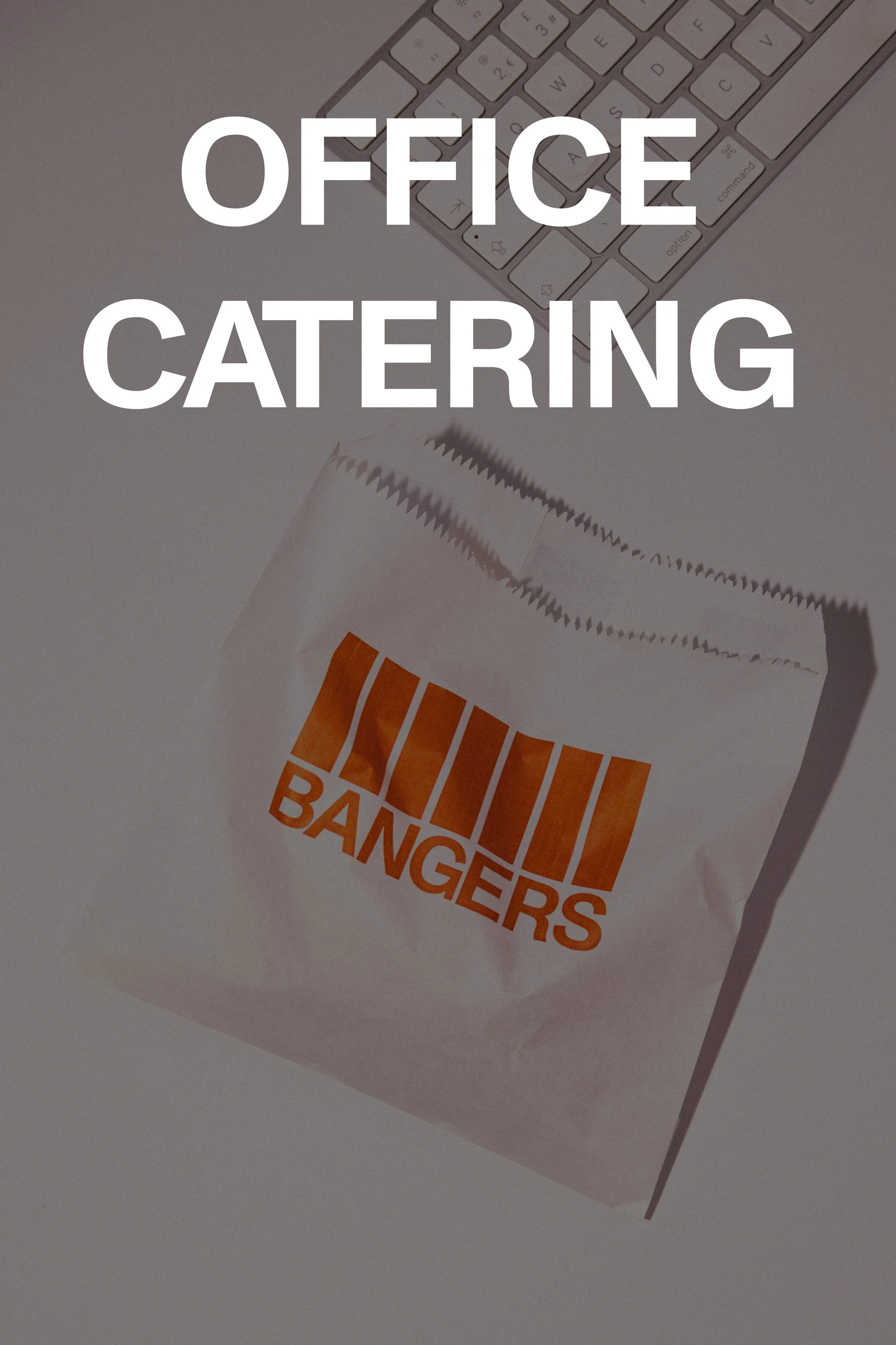 A white paper bag with orange and black "BANGERS" logo on it, placed on a white surface next to a computer keyboard.