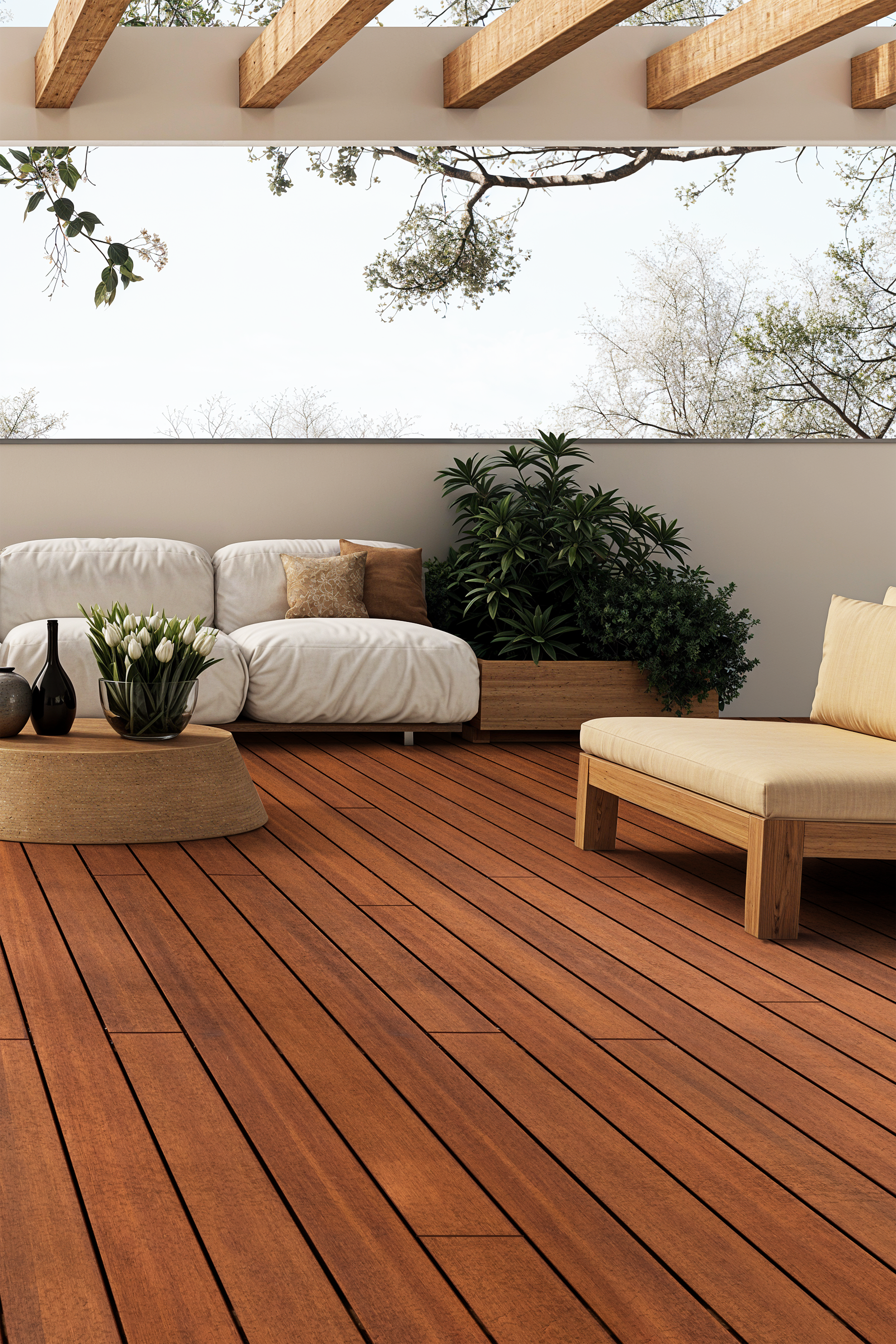 Varanda com deck de madeira, móveis de exterior com almofadas brancas e bege, plantas verdes em vasos de madeira, vista para o céu e árvores pelo muro de vidro.