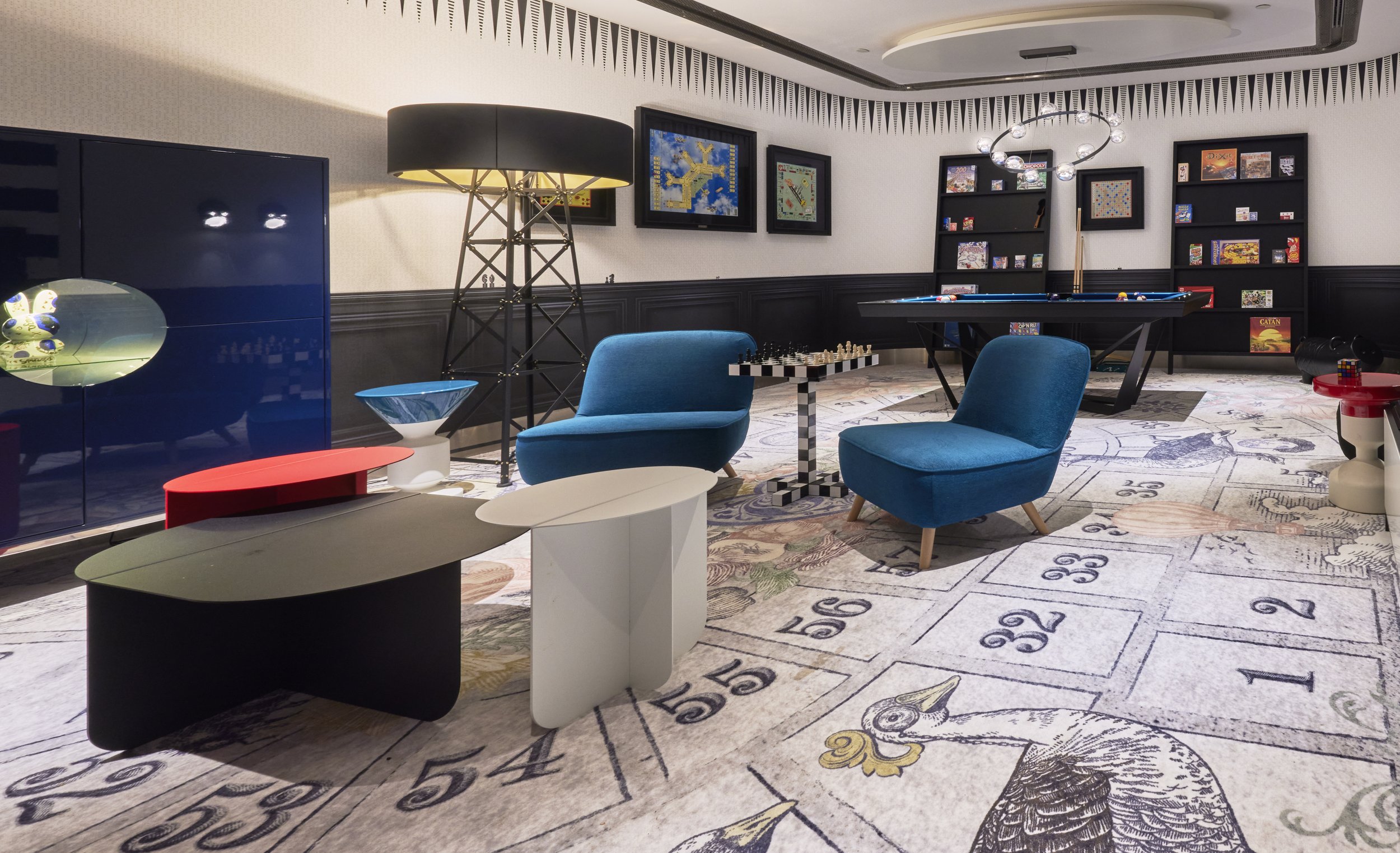 Interieur van een speelhoek met basketbal, biljart, boekenplanken en fauteuils.