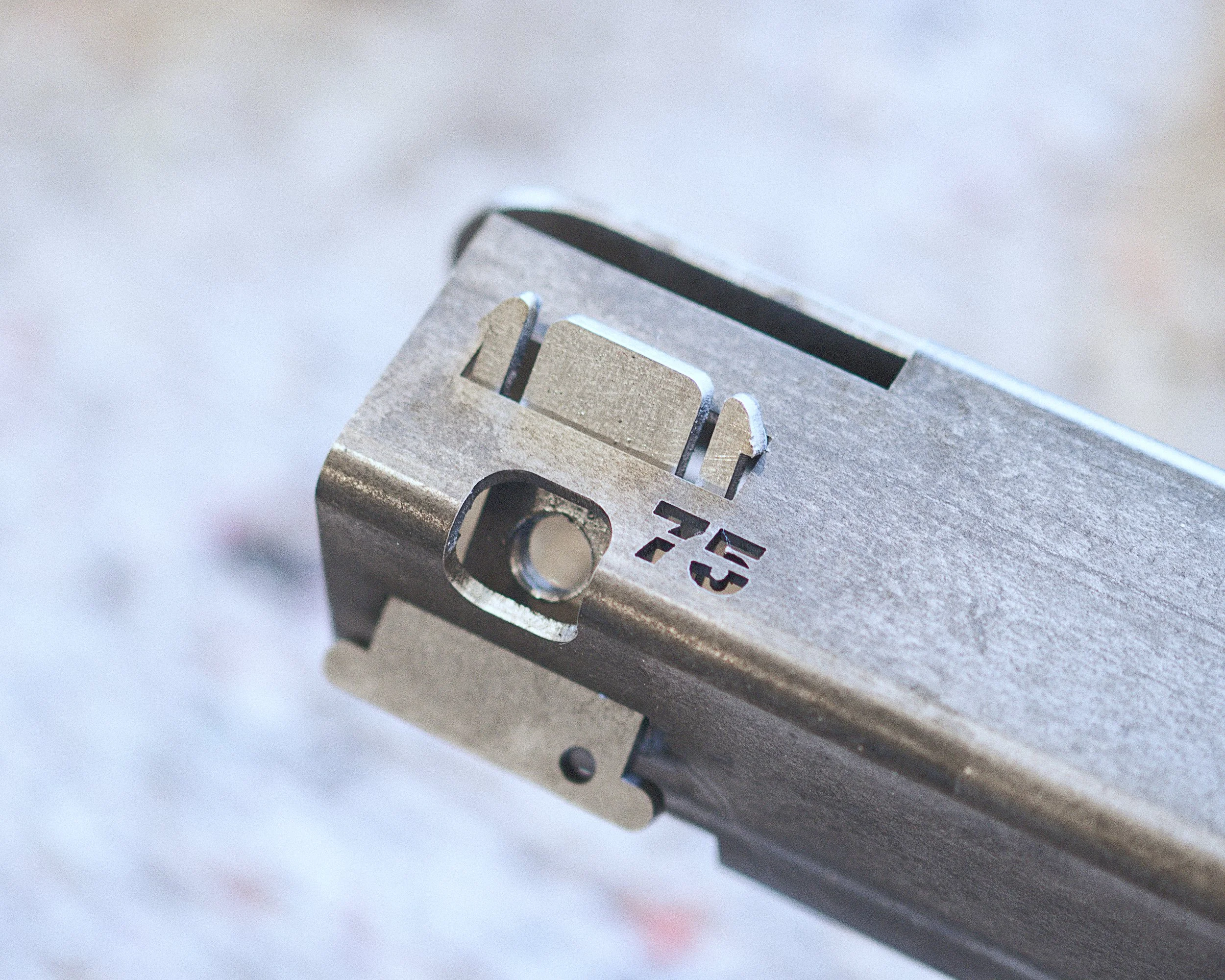 Dichtbijzicht van een metalen sluitstuk of mechanisch onderdeel met afdruk en inscripties.