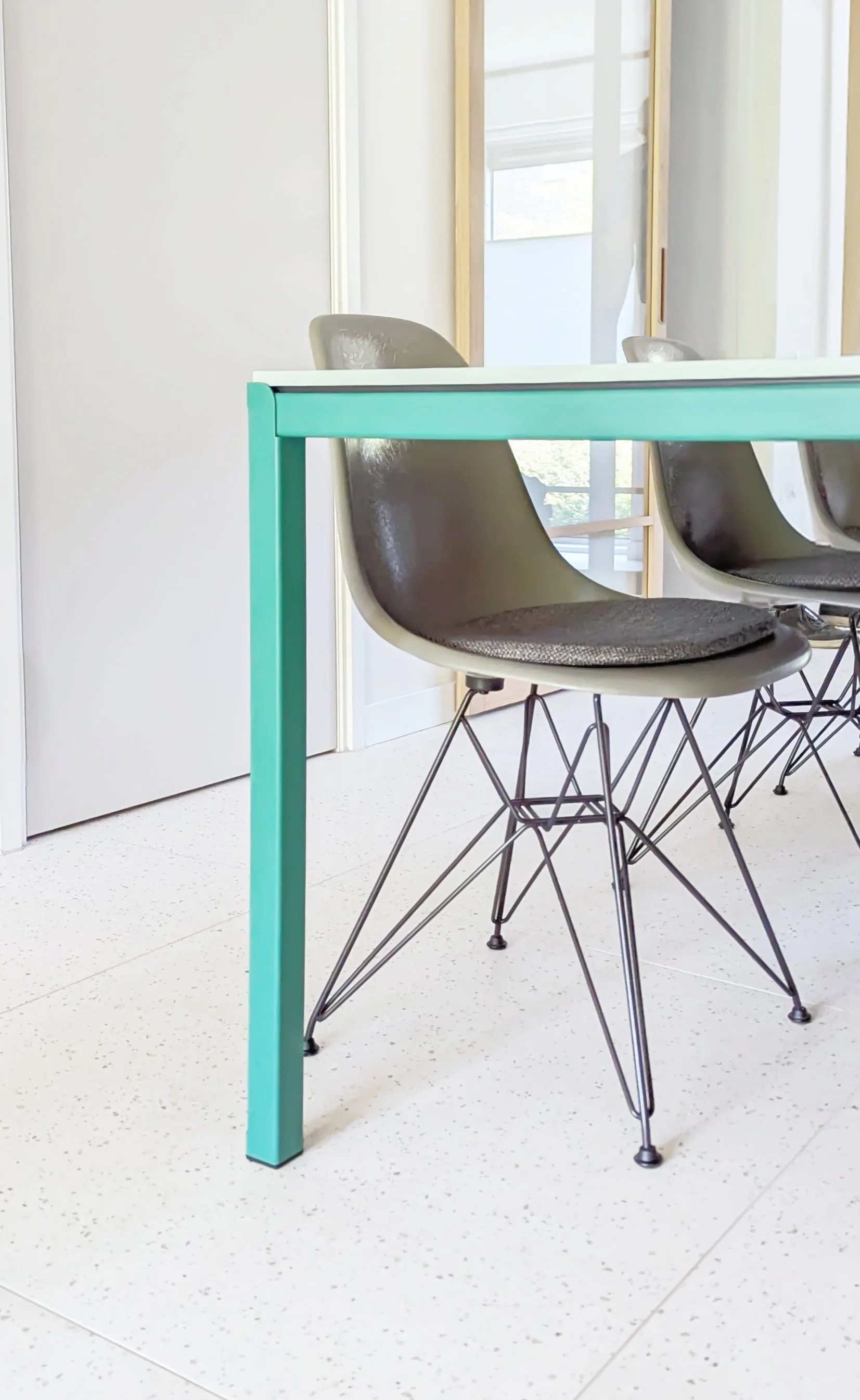 Kant met grijze stoelen in een verlichte kamer met grote ramen.