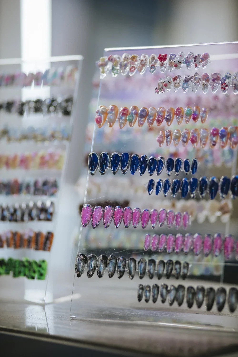 Display of colorful nail art stickers arranged in rows on a clear stand, with various designs and vibrant colors.