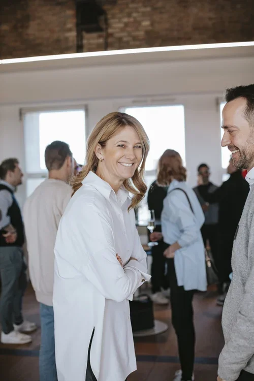 Two people smiling and engaging in conversation at a social gathering or networking event.