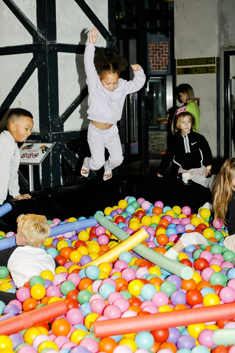 Children playing in a colorful ball pit at an indoor playground.