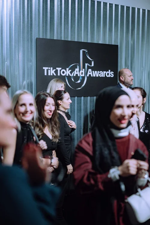 Group of people at TikTok Ad Awards event, standing in front of a black wall with TikTok logo and event signage.