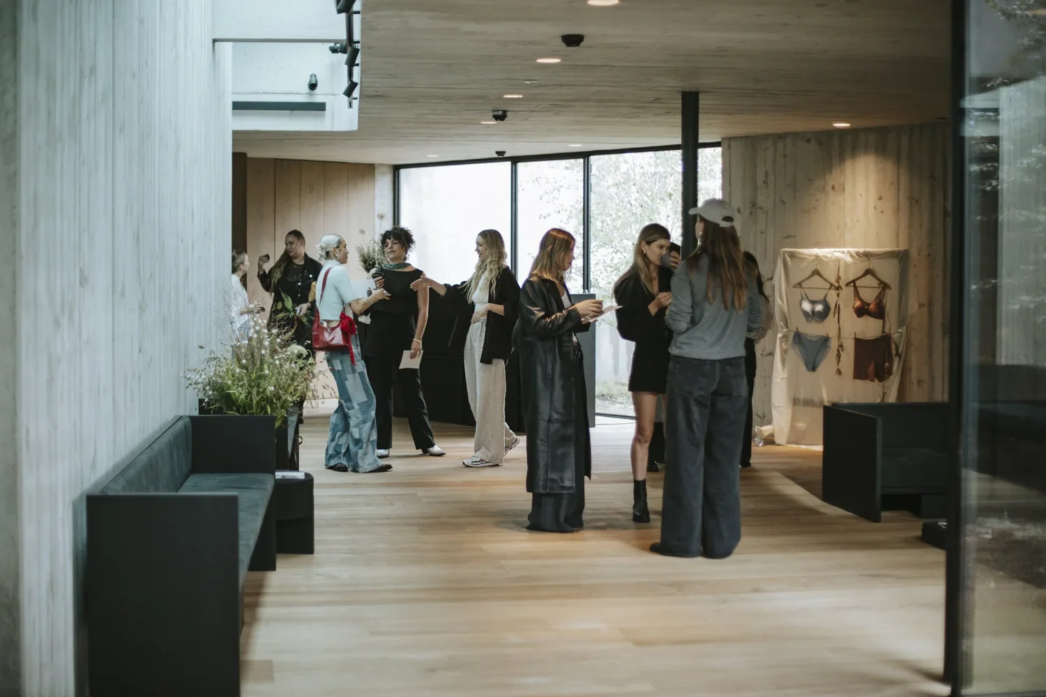 Group of women socializing and shopping at a boutique or retail store with lingerie display and large windows in modern interior