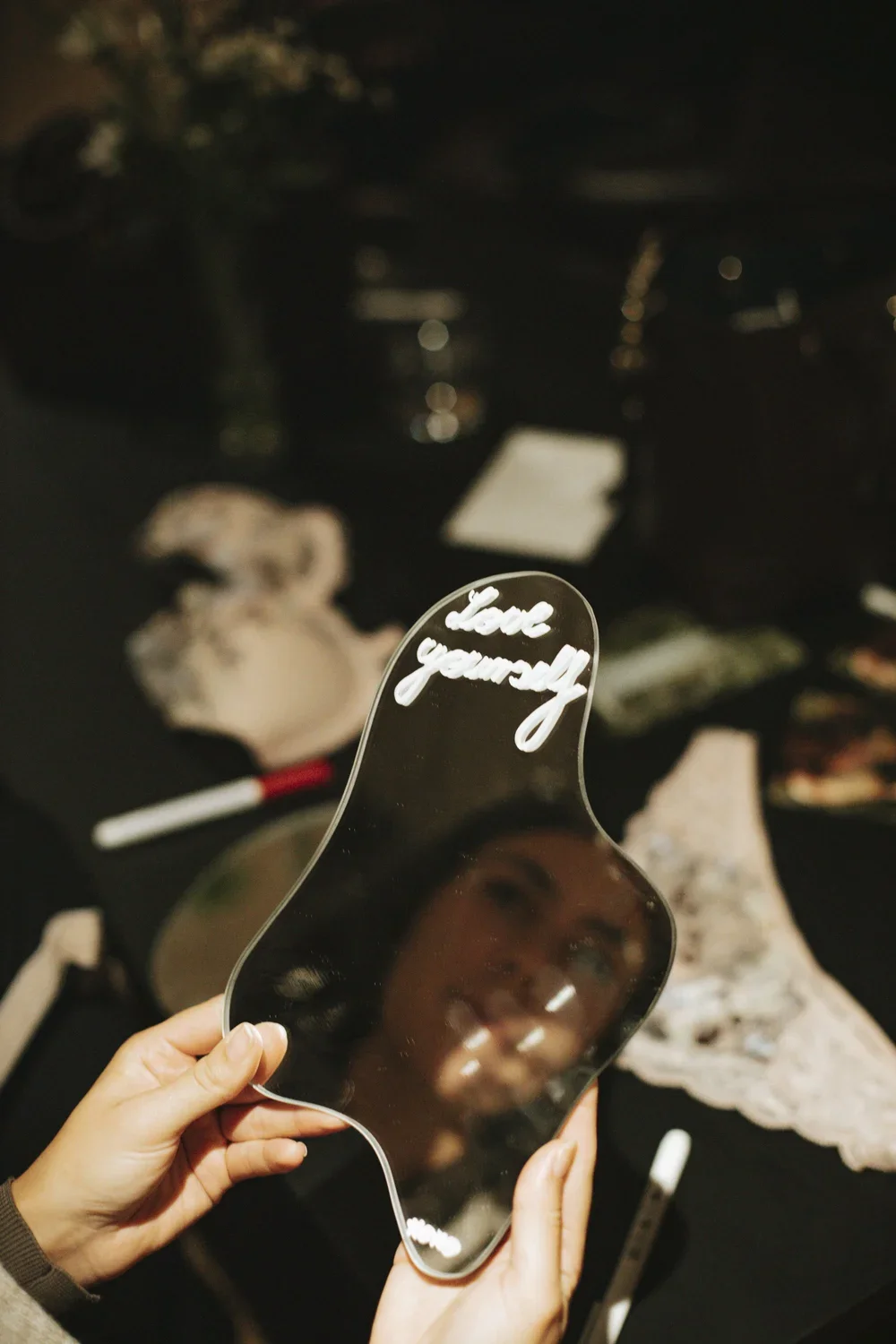 Person holding a mirror with the words "love yourself" written on it, reflecting their face.