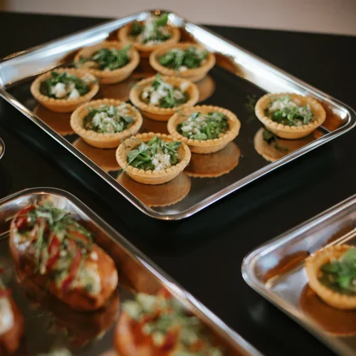 Tray of mini savory tarts topped with herbs and cheese.