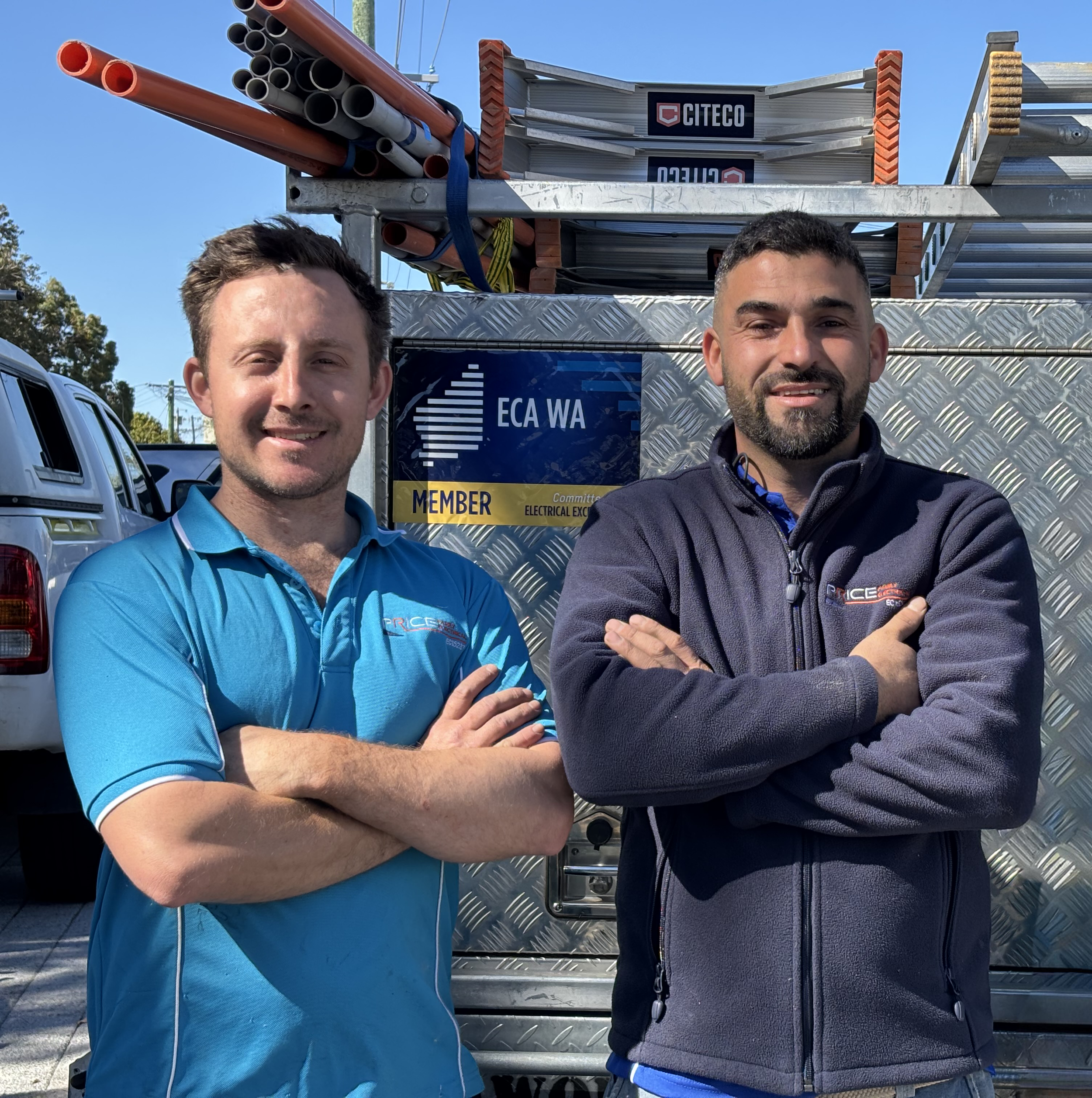 image of two electricians from Price Family Electrical standing in front of a work vehicle with an ECA WA  member sticker showing. They are standing in front of a commercial premise