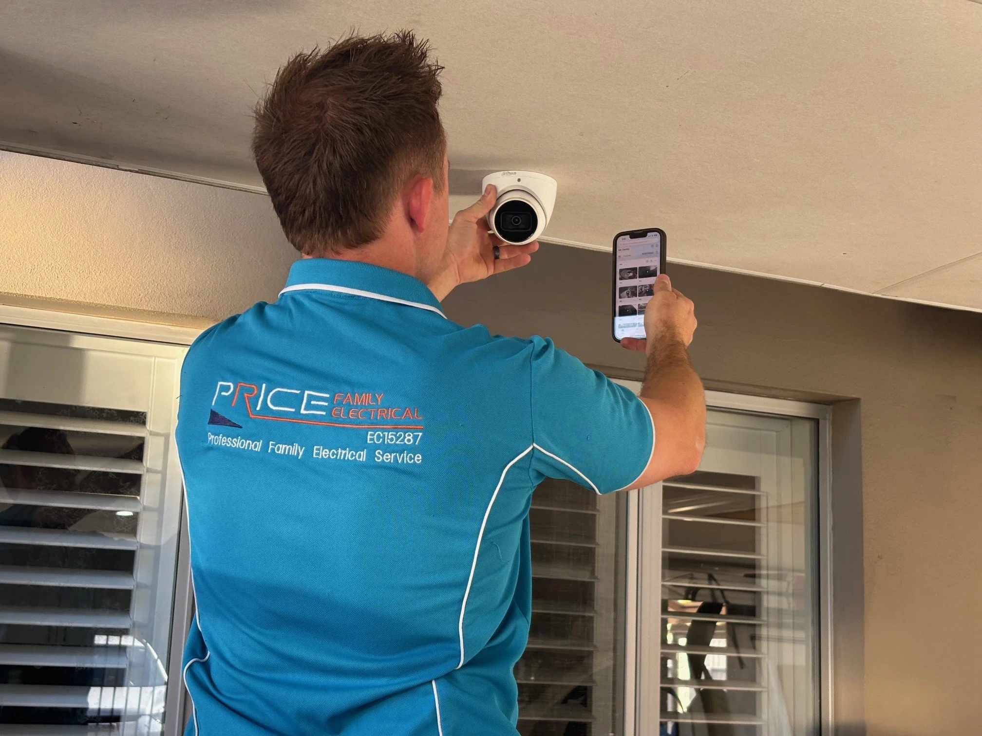 image of an electrician setting a CCTV camera with remote viewing in a driveway Perth residential electricians