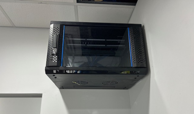 Black server rack mounted on a white wall by Price Family Electrical in Perth