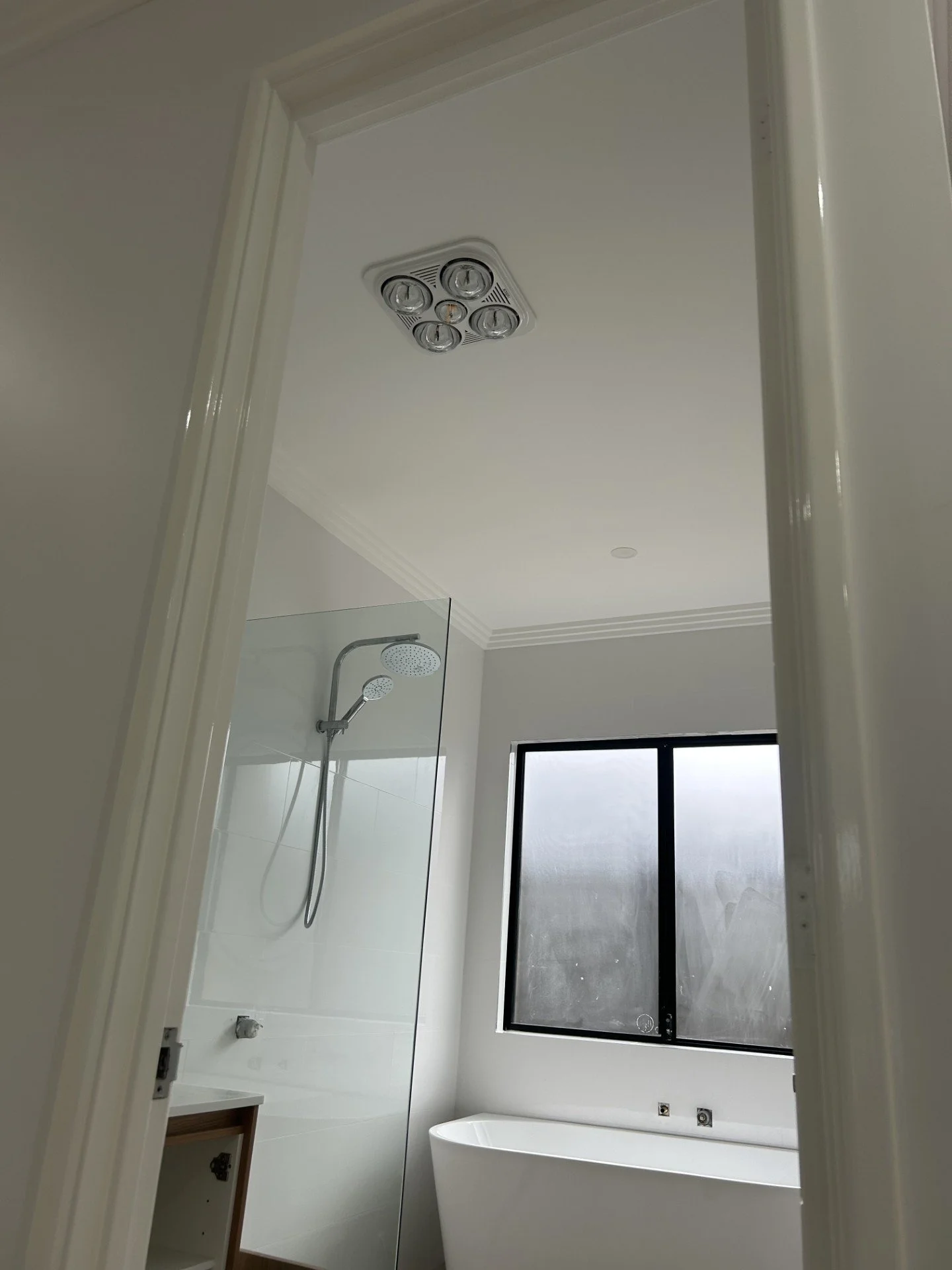 Image of a newly build bathroom, highlighting an IXL heat lamp light and a downlight installed by Perth residential electricans