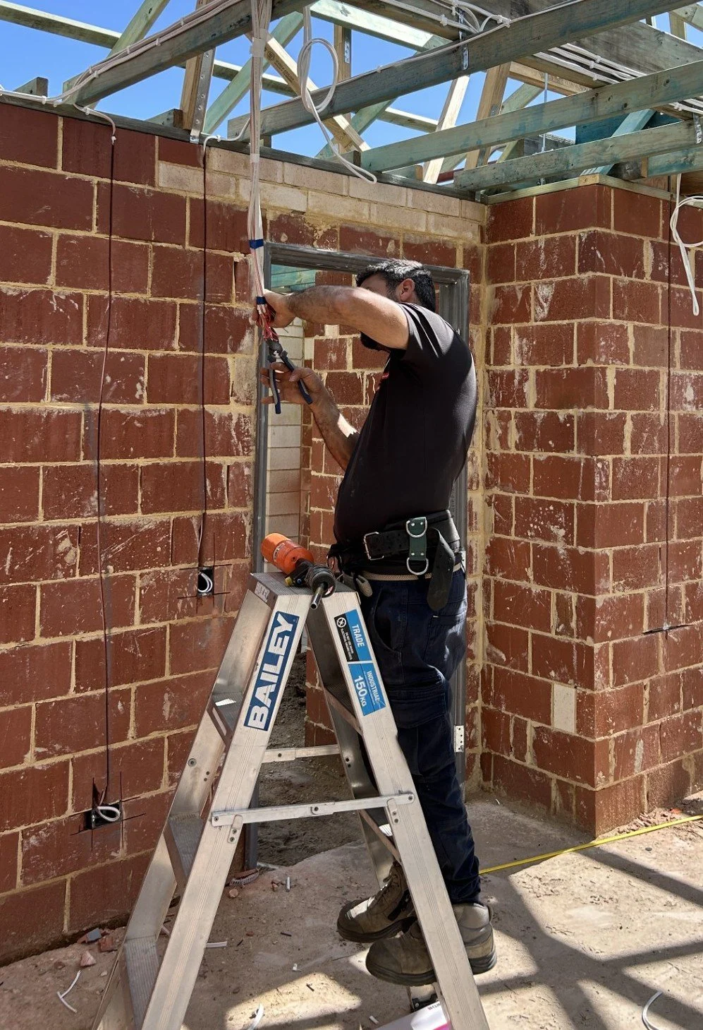 image of an electrician from Price Family Electrical installing wiring in a new home being built